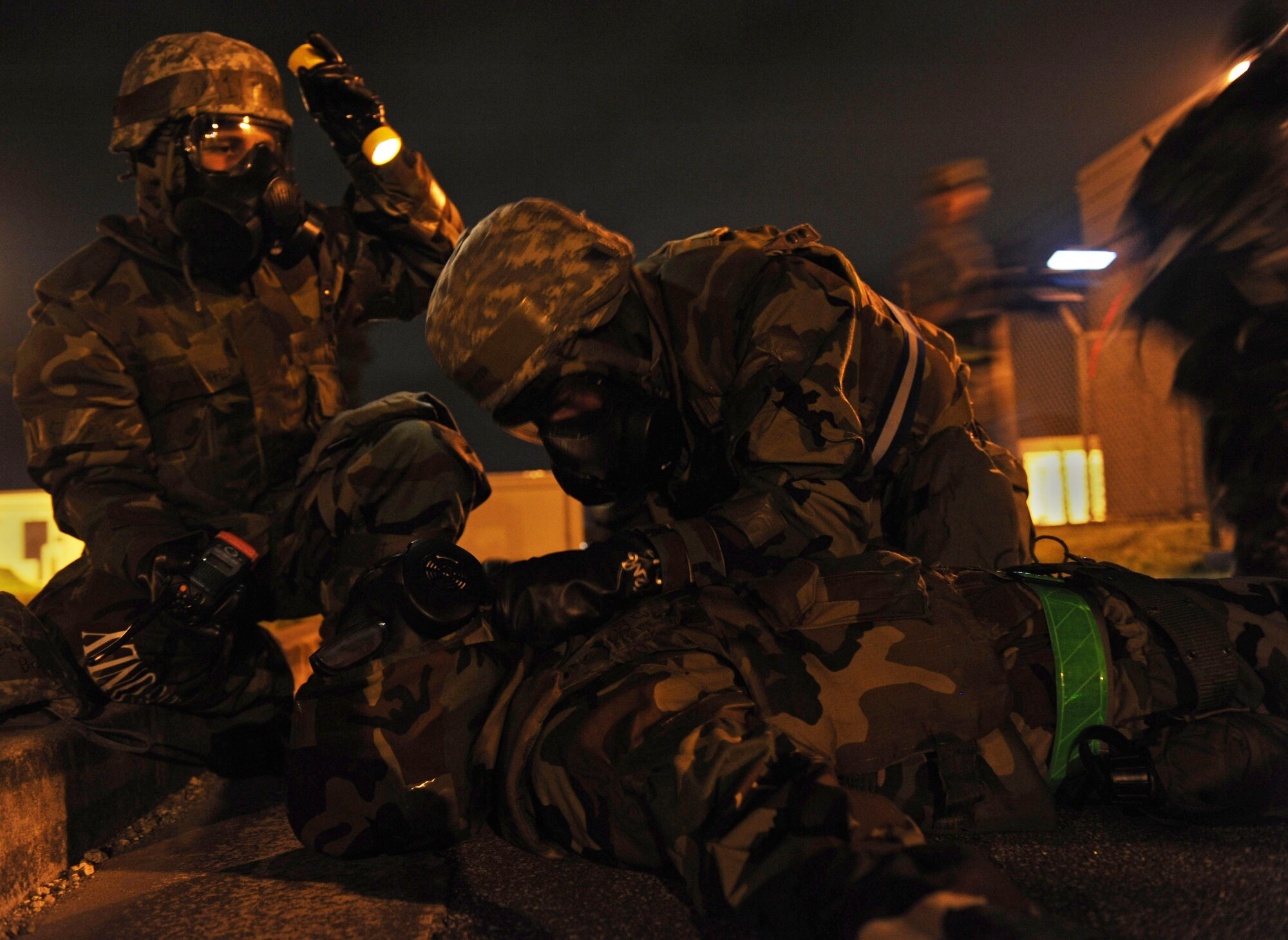 U.S. Air Force Airman 1st Class Jordon Gauthier and 1st Lt. Bryan Hoffler, 18th Communications Squadron network infrastructure technician and officer in charge of cyber operations, puts Mission-Oriented Protective Posture gear on Airman 1st Class Ethen Bradley, 18th Communications Squadron cyber transport technician, during local operational exercise on Kadena Air Base, Japan, Aug. 24, 2012. MOPP gear protects an individual from chemical agents during attacks. (U.S. Air Force Airman 1st Class Malia Jenkins/photo)  