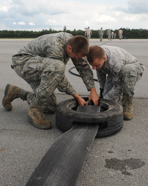 U.S. Air Force Senior Airmen Ryan Sheive (left) and James Park, 4th Civil Engineer Squadron power production journeymen, connect a pendant cable on Seymour Johnson Air Force Base, N.C., Aug. 21, 2012. The pendant cable catches the landing hook an F-15E Strike Eagle drops in a case of an in-flight-emergency involving brake failure. (U.S. Air Force photo/Airman 1st Class John Nieves Camacho/Released)