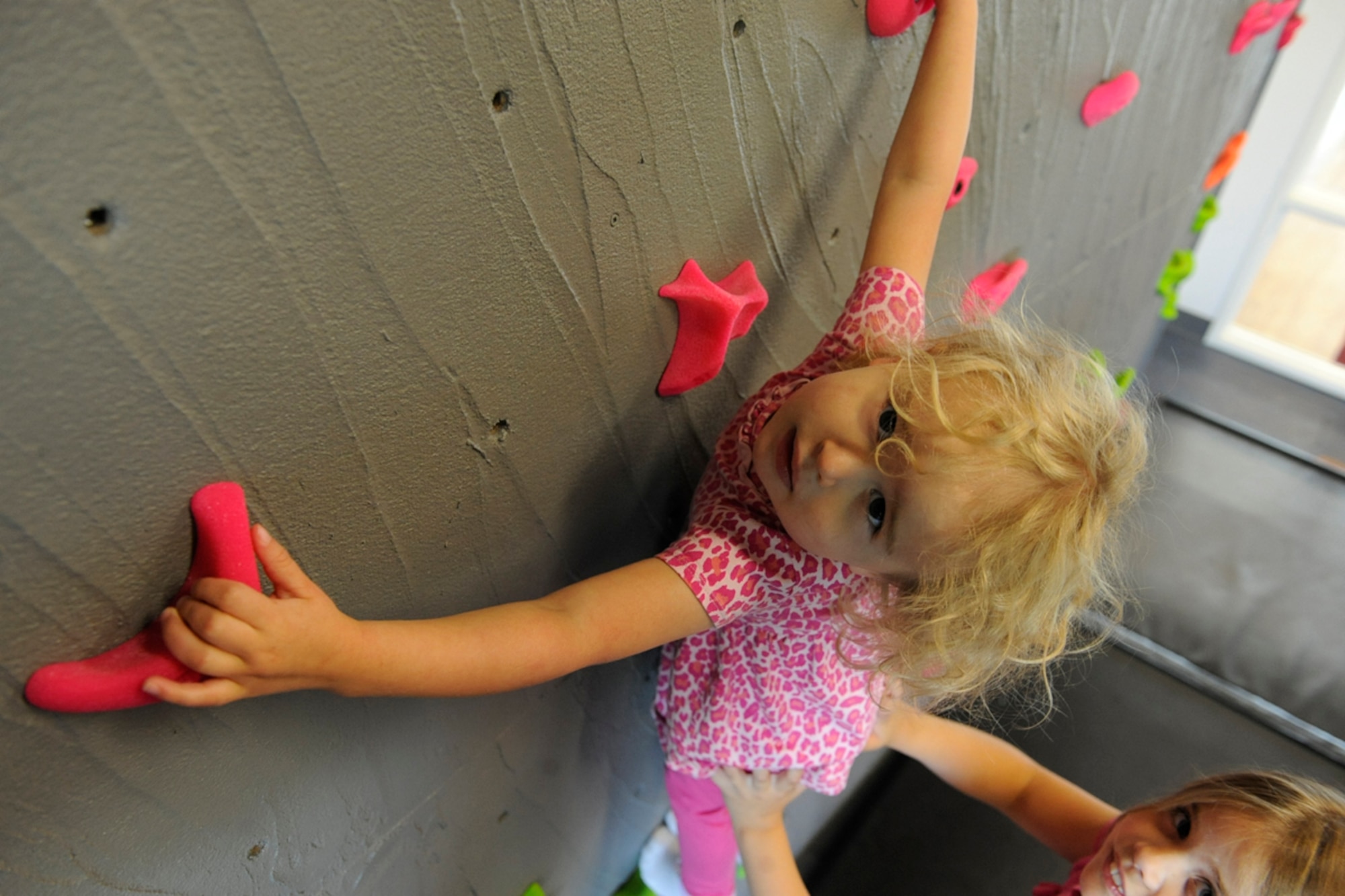 Laura Beatty, 9, helps her sister, Arya Beatty, gets started on the rock climbing wall in the children's play area at the Richardson Community Center on JBER, Aug. 21. The Richardson Community Center, housed in Building 338, labeled 'Aurora Military Housing,' was officially opened for business Aug. 20. Their father is Cpl. Charles Beatty, a member of the 3rd Battalion (airborne) 509th Infantry Regiment. Their hometown is Reno, Nev. (U.S. Air Force photo/Staff Sgt. Robert Barnett)