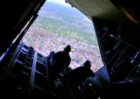 A U.S. Department of Agriculture wildlife biologist, left, and a military videographer are silhouetted aboard the open ramp of a 919th Special Operations Wing MC-130 as it banks over woodlands near Duke Field, Fla. The Air Force Reserve wing supported the department’s request for an aerial photography flight to document wildlife habitats that can create aviation hazards, such as bird strikes, at Duke Field and Eglin Air Force Base. (U.S. Air Force photo/Dan Neely)
