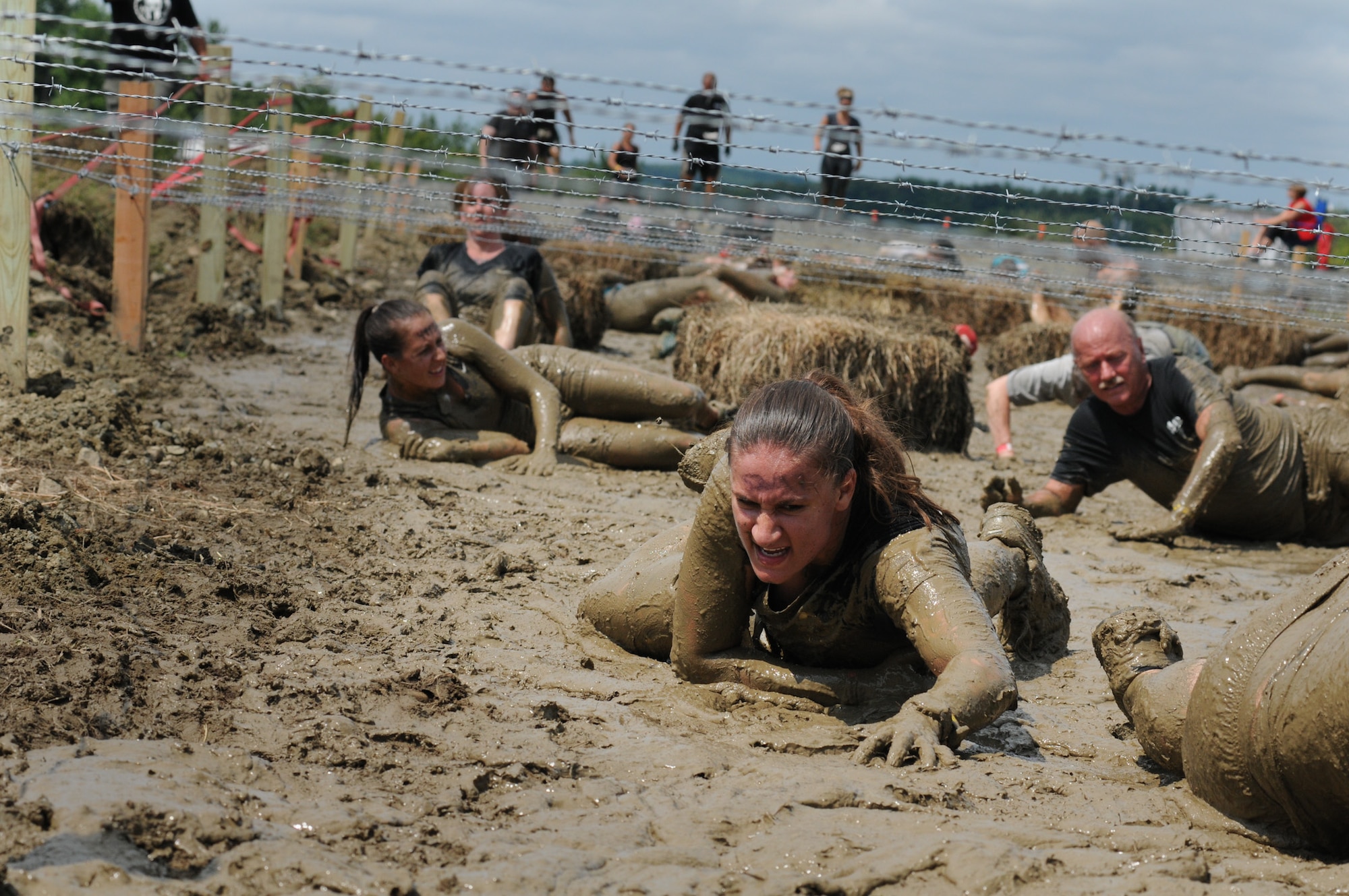Staff Sgt. Ashley Davin, 102nd Security Forces Squadron, low crawls through the mud in Amesbury, Mass., Aug. 11, 2012. Davin was participating in the Spartan Race, testing her strength, endurance, and resilience against a course of challenging obstacles. (Air National Guard photo by Senior Airman Jeremy Bowcock/Released)