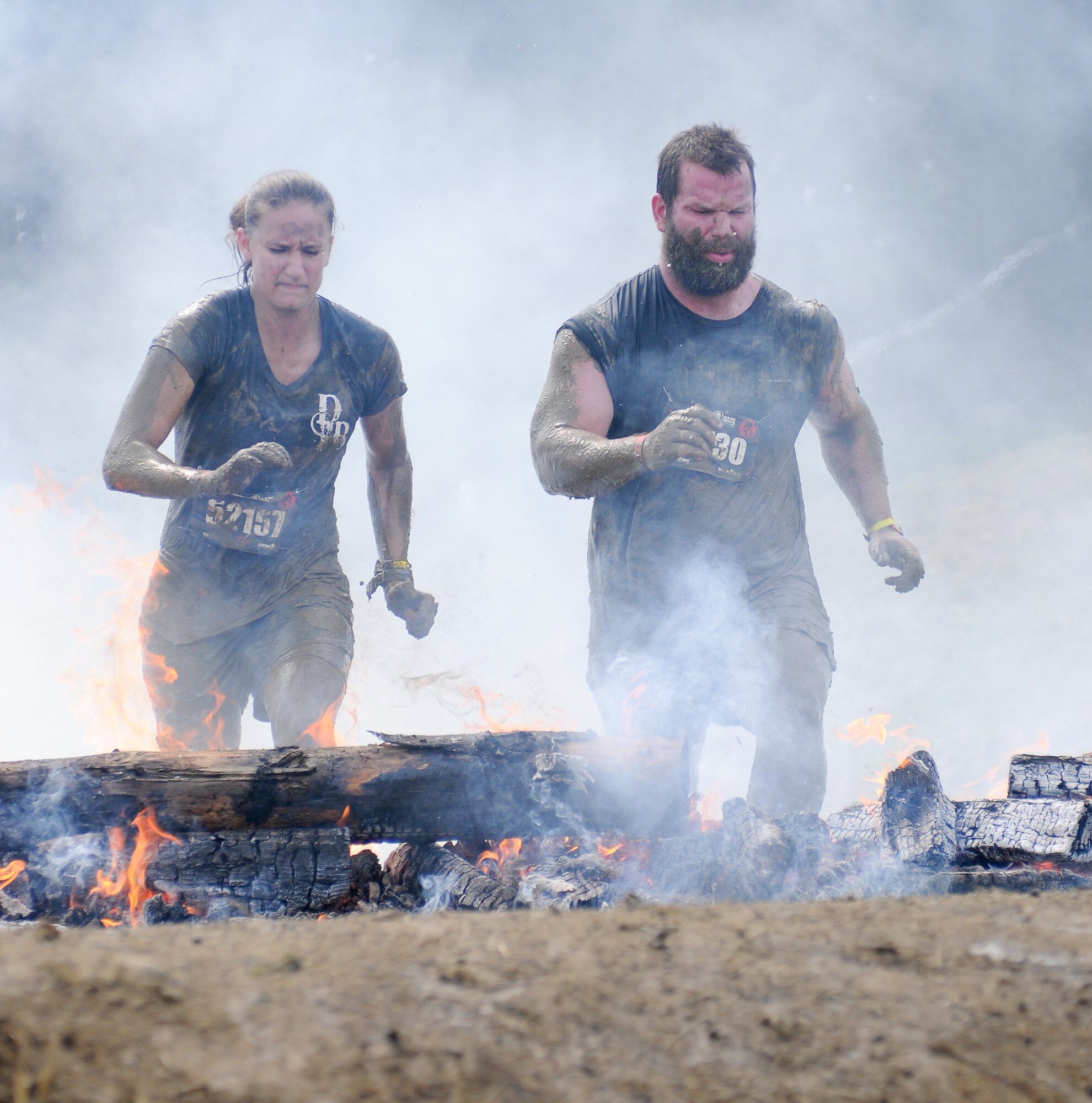 Staff Sgt. Ashley Davin, 102nd Security Foces Squadron, and another competitor run through fire in Amesbury, Mass., Aug. 11, 2012. Davin was participating in the Spartan Race, testing her strength, endurance, and resilience against a course of challenging obstacles. (Air National Guard photo by Senior Airman Jeremy Bowcock/Released)