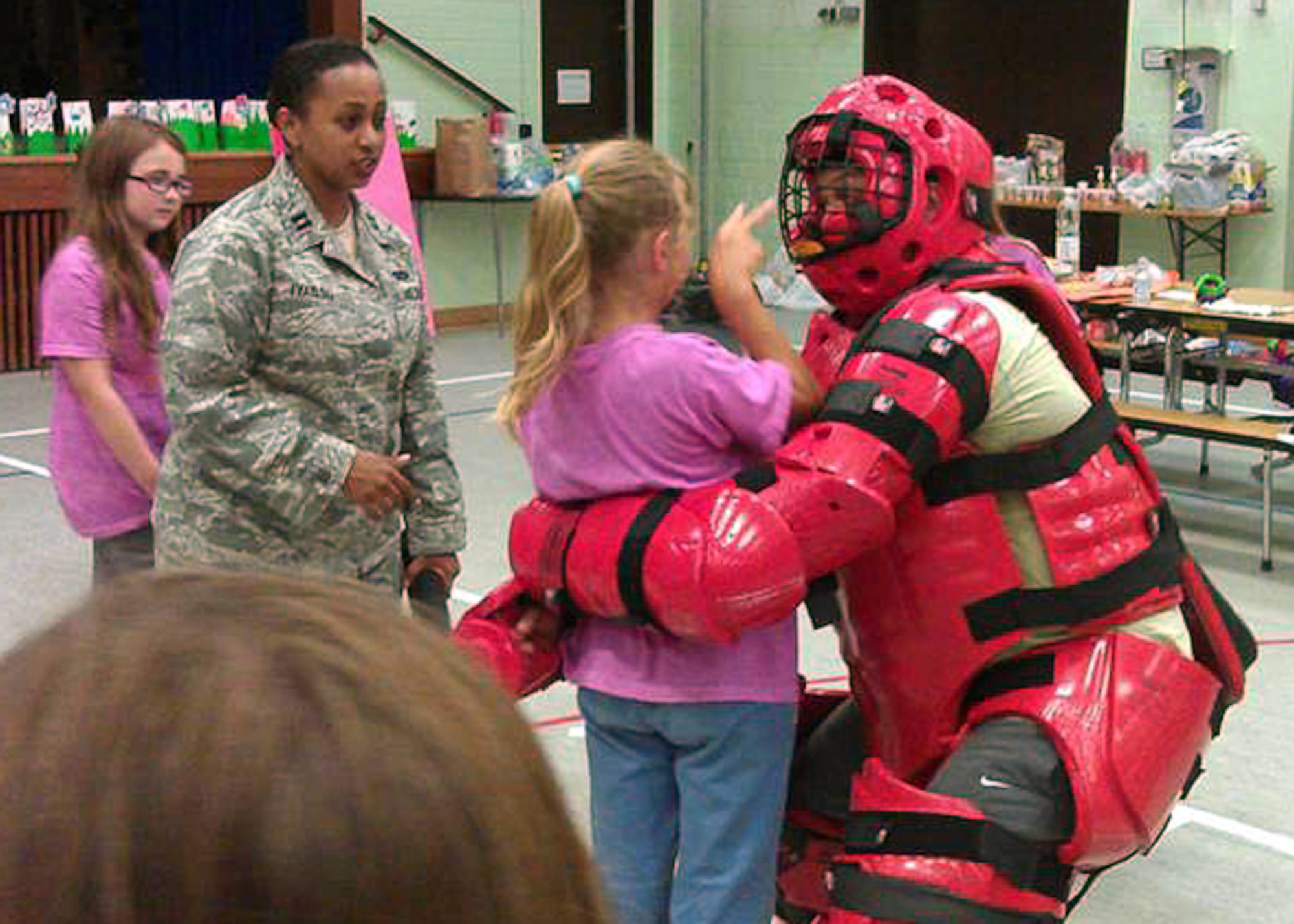 SPANGDAHLEM AIR BASE, Germany -- Capt. Lidia Iyassu, 52nd Security Forces Squadron, instructs Girls Scouts from USA Girl Scouts Overseas at the Spangdahlem Elementary School here Aug. 21 during a summer camp. The Girl Scouts partnered with the 52nd SFS to learn techniques in identifying and reacting to strangers, basic defensive striking techniques, and strategies for getting attention during an emergency. The tactics can be used against possible abductors, as portrayed here by Master Sgt. DeJanairo Wilson, 52nd SFS, wearing a combatives suit. (U.S. Air Force photo by Tech. Sgt. Jose De Jesus/Released)