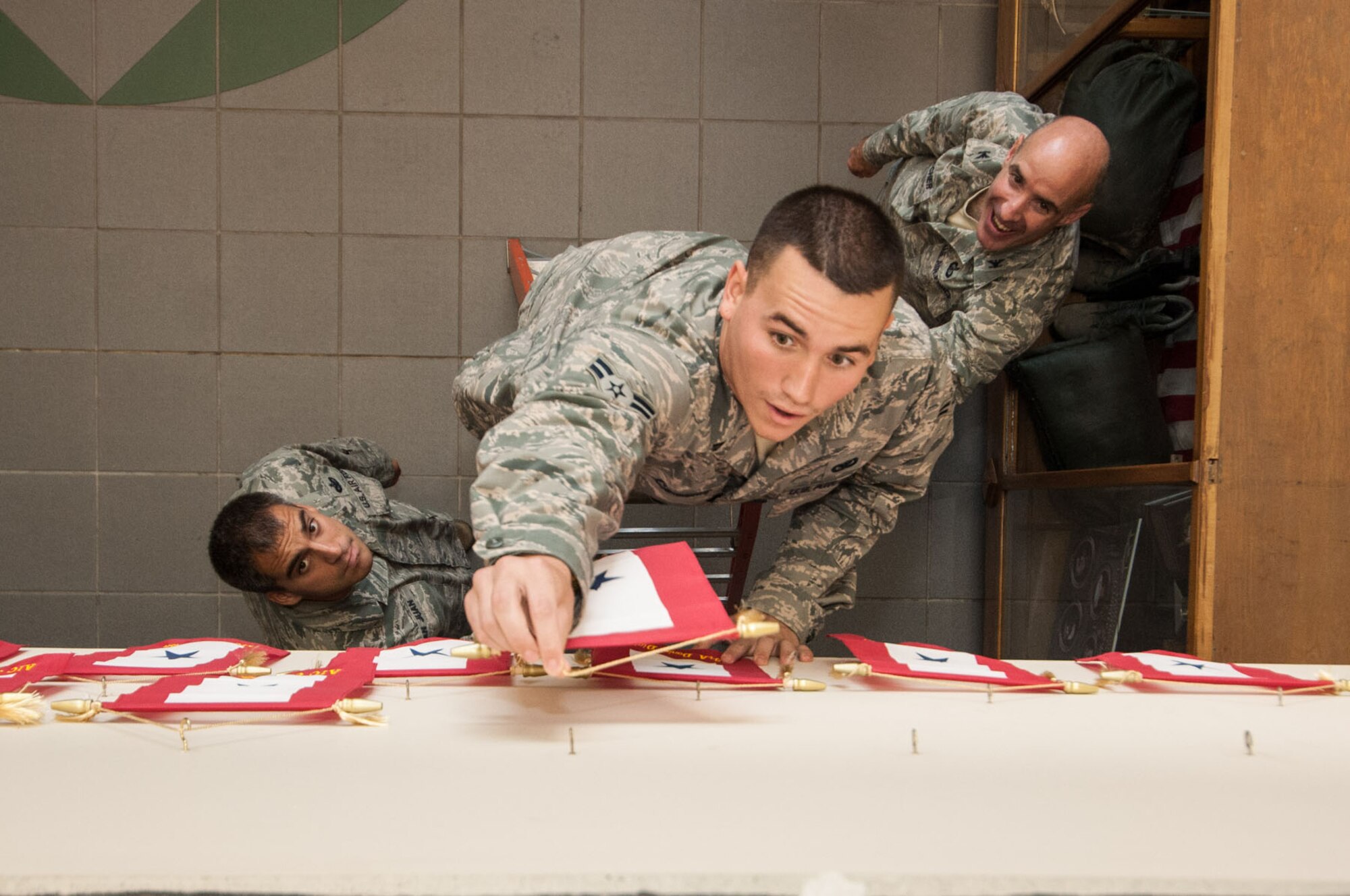 HANSCOM AIR FORCE BASE, Mass - Airman 1st Class Paul Cardona of the 66th Security Forces Squadron hangs his service banner on Aug. 17 in the atrium of Building 1725 as part the squadron’s tradition for troops that are deploying. A group of SFS members are headed to Southwest Asia on a deployment to provide combat airpower and support for Operations New Dawn and Enduring Freedom and in support of the Combined Joint Task Force-Horn of Africa. (U.S. Air Force photo by Rick Berry)