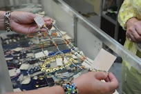Sara Stulga (right), Thrift Shop volunteer, looks on as Susie Parson from Air Force Personnel Center finds a necklace at the thrift shop on Joint Base San Antonio-Randolph, Texas, Aug. 20. Proceeds from the Thrift Shop sales goes to college scholarships for high school students. (U.S. Air Force photo by Rich McFadden) 