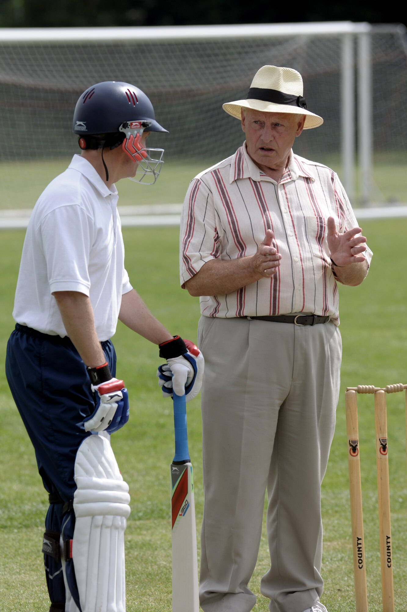 LONGSTANTON, United Kingdom – Lt. Col. Jonathan Bradley, 423rd Air Base Group, gets some tips from Derek Stebbing, 423rd Communications Squadron honorary commander, before batting during the first game played by the team Aug. 19 at Longstanton Bowls Club in Longstanton, United Kingdom. The primary concern of the batsman on strike (i.e., the "striker") is to prevent the ball hitting the wicket and secondarily to score runs by hitting the ball with his bat so that he and his partner have time to run from one end of the pitch to the other before the fielding side can return the ball. To register a run, both runners must touch the ground behind the crease with either their bats or their bodies (the batsmen carry their bats as they run). Each completed run increments the score. (U.S. Air Force photo by Master Sgt. John Barton)