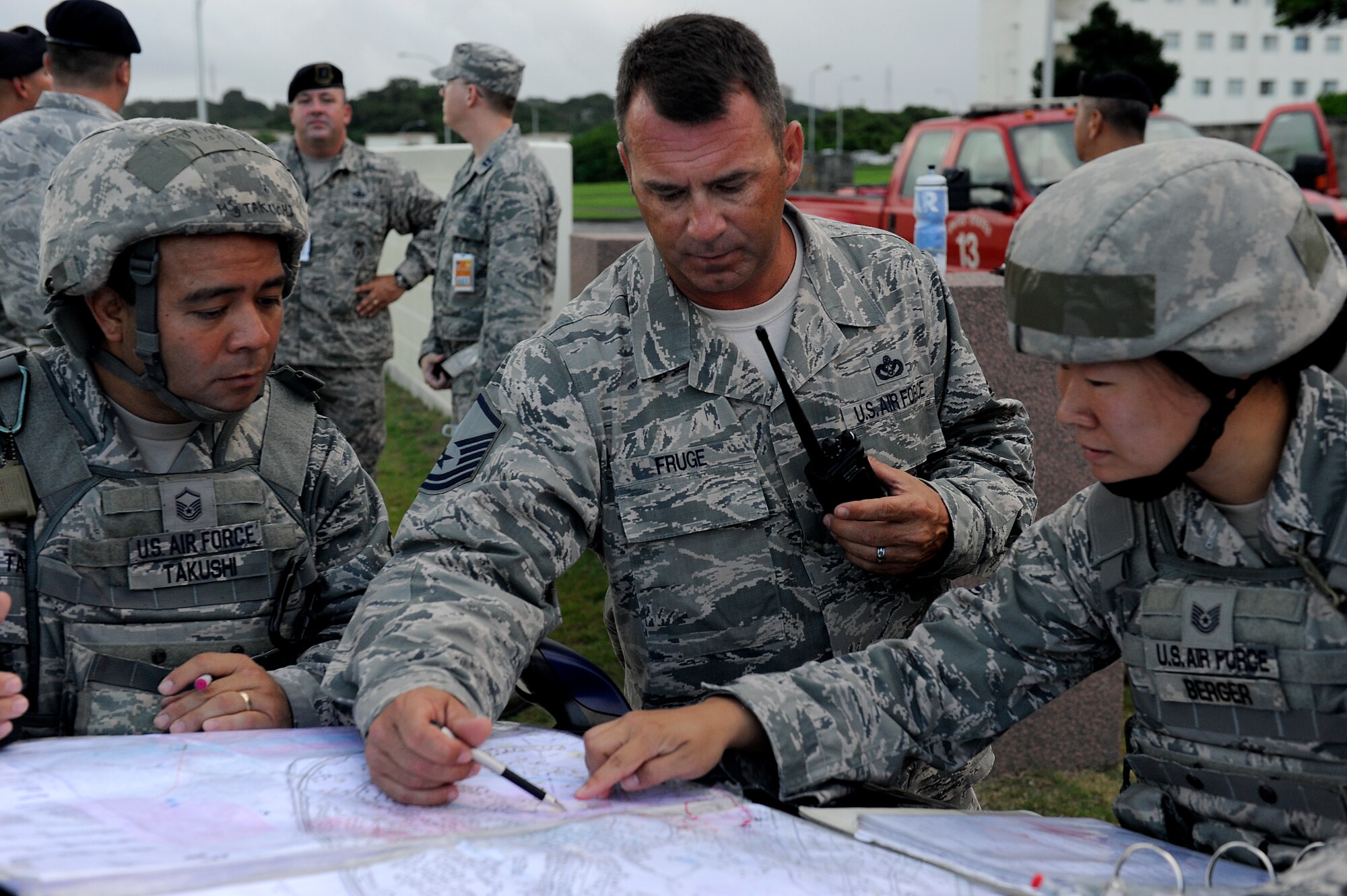 (From left to right) U.S. Air Force Master Sgt. Bradley Takushi, Master Sgt. Joseph Fruge, and Tech. Sgt. Lauren Berger, consult a map to initiate containment of an exposed area during an emergency management exercise as part of Beverly High 12-5, a local operational readiness exercise on Kadena Air Base, Japan, Aug. 22, 2012. The EME tested Kadena Airmen's ability to respond, properly contain and decontaminate a possible anthrax threat on the base. Takushi and Berger are both assigned to the 18th Security Forces Squadron, while Fruge is assigned to the 18th Civil Engineer Squadron Fire Department. (U.S. Air Force photo/Senior Airman Maeson L. Elleman)