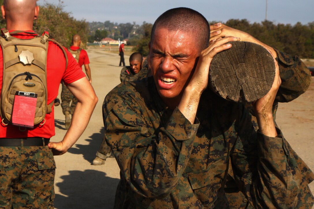 Recruit Jared Jansen, Platoon 1001, Company A, 1st Recruit training Battalion, exerts his energy as he squats with a log over his shoulder during recruit training aboard Marine Corps Recruit Depot San Diego Aug. 14. Recruits built teamwork as they executed log drills in order to accomplish the rigorous training.