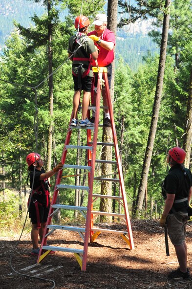 Will Parks, Adventure Dynamics instructor, hooks John, a member of the DARE summer camp, up to the zip-line swing while the ladder safety team, Staff Sgt. Brooke Williams and Greg Stewart stand close by Aug. 22, 2012 at Adventure Dynamics in Nine Mile Falls, Washington. Williams and Greg are both members of the 92nd Security Forces Squadron. (U.S. Air Force photo by Airman 1st Class Earlandez Young) 