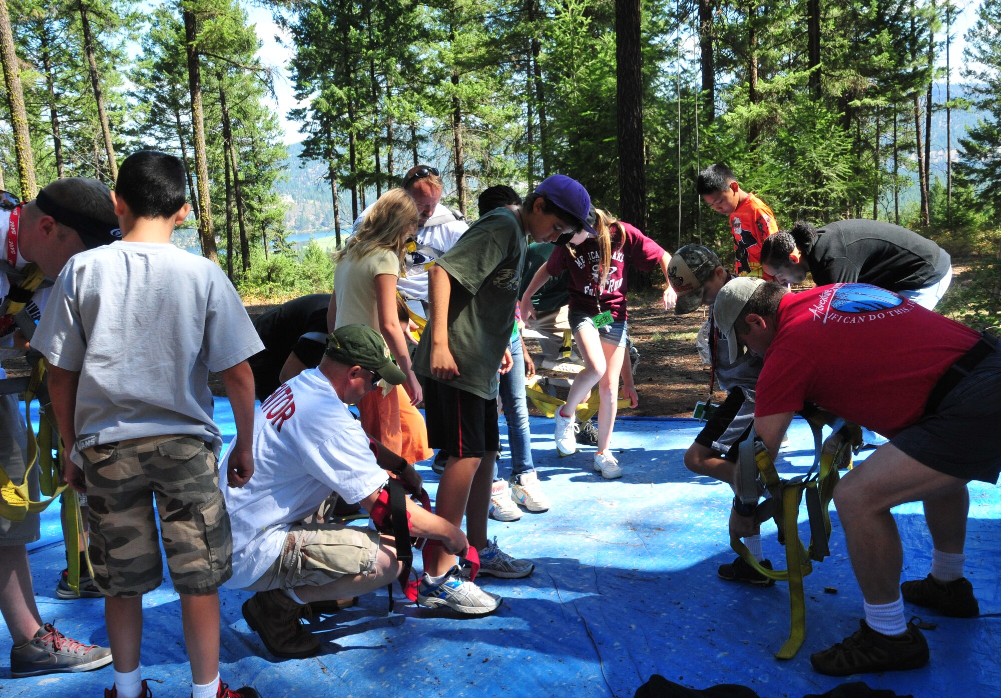 D.A.R.E. summer camp mentors and Adventure Dynamics instructor Will Parks straps children into their harnesses so they can advance to the next activity, which was the zip-line swing Aug. 22, 2012 at Adventure Dynamics in Nine Mile Falls, Washington. (U.S. Air Force photo by Airman 1st Class Earlandez Young)