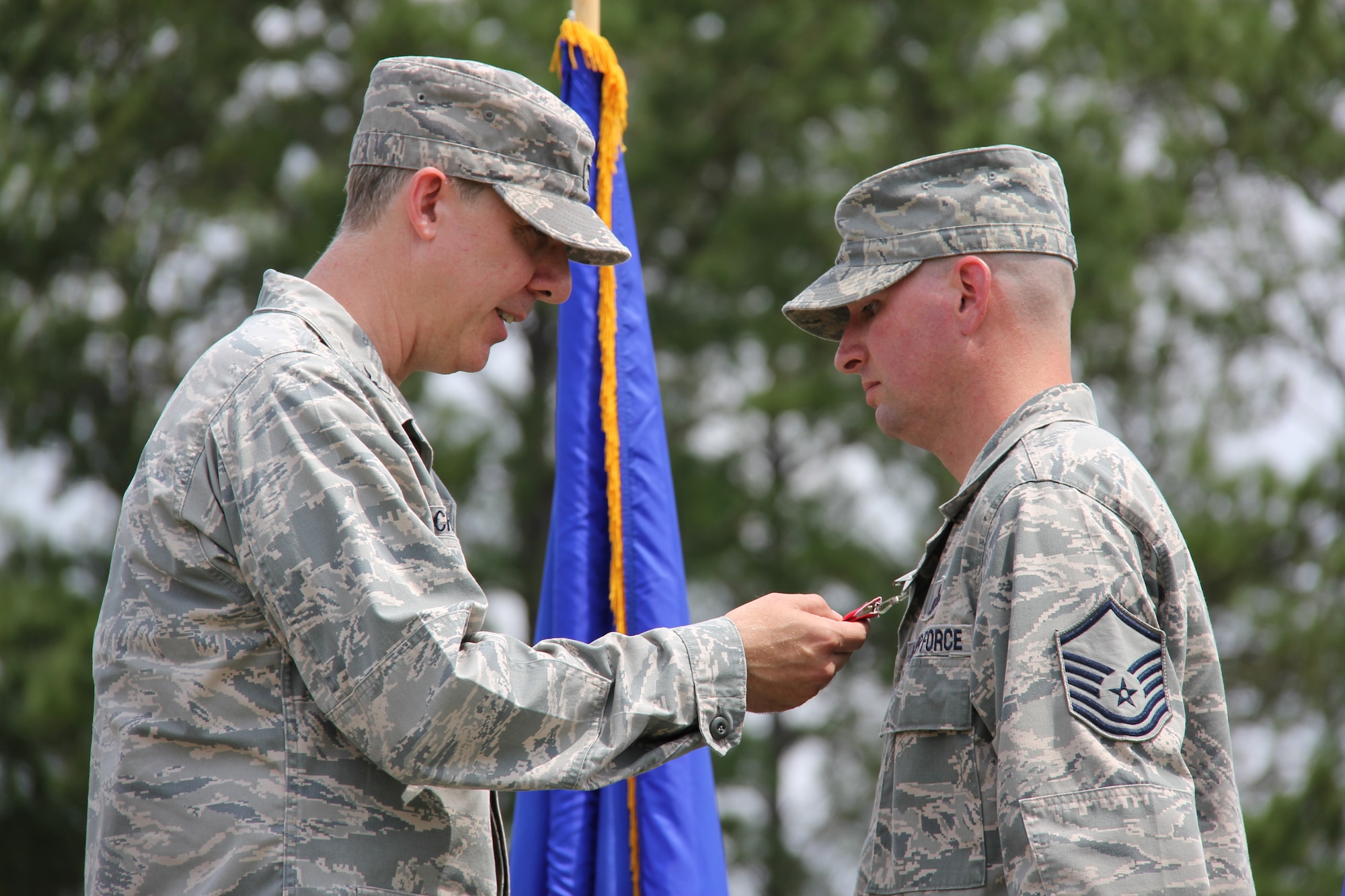 ROBINS AIR FORCE BASE, Ga. -- Col. Joseph Scherrer, 689th Combat Communications Wing commander, presents Master Sgt. Gene Jameson, III, 689th CCW wing policy manager, with the Bronze Star with Valor, August 23 at the South Training Area, Robins Air Force Base. More than 450 combat communicators participated in recognizing the senior non-commissioned officer's decoration. Jameson was deployed to Bagram, Afghanistan, and battled a fire started by an insurgent’s 107-millimeter rocket. (U.S. Air Force photo by Robert Talenti)