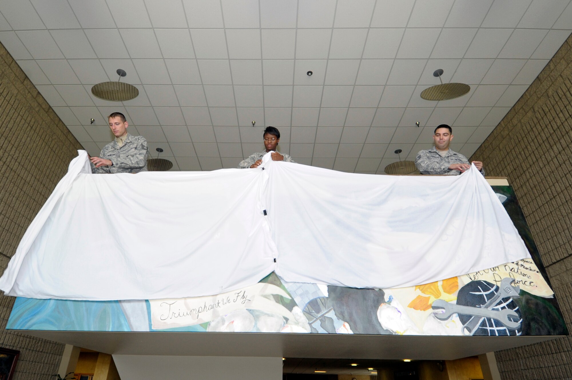 VANDENBERG AIR FORCE BASE, Calif. -- 381st Training Support Squadron members, Tech. Sgt. Trevor McIntyre, Airman 1st Class Eboni Alexander and Staff Sgt. Rafael Perez, unveil a mural representing the heritage of the 381st Training Group during a ceremony here, August 23, 2012. Alexander designed the mural and led the team depicting the three main eras of the unit; the 381st Bombardment Group, the 381st Strategic Missile Wing, and the 381st Training Group. (U.S. Air Force photo/Jerry E. Clemens Jr.)