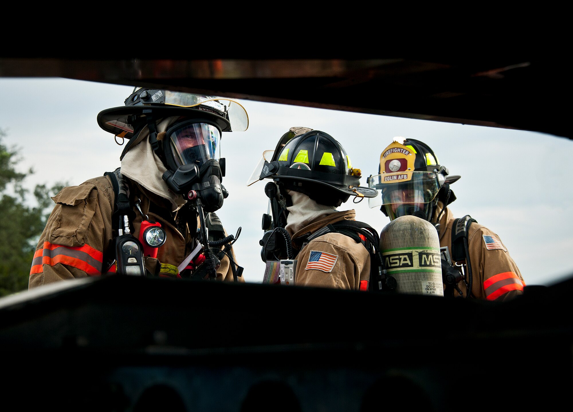 Matthew Becker, Amber Turek and Airman 1st Class Brandon Rudolph, 96th Test Wing firefighters, discuss vehicle inspection procedures after successfully putting out a simulated truck fire during a Nuclear Accident Response Exercise at Eglin Air Force Base, Fla., Aug. 22.  Eglin agencies, including first responders, were evaluated on their reactions and responses to a vehicle explosion carrying nuclear material.  (U.S. Air Force photo/Samuel King Jr.)