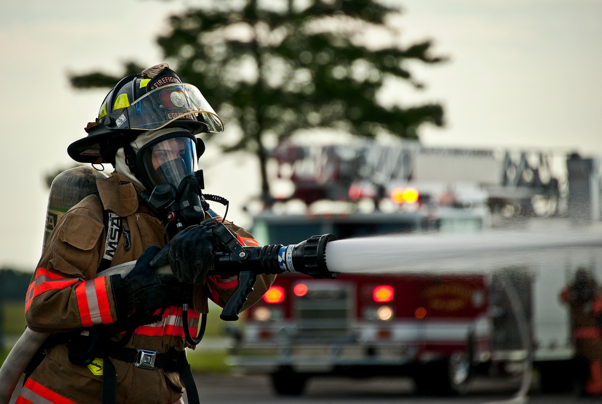 Amber Turek, a 96th Test Wing firefighter, attacks the simulated fire at the rear of the truck during a Nuclear Accident Response Exercise at Eglin Air Force Base, Fla., Aug. 22.  Eglin agencies, including first responders, were evaluated on their reactions and responses to a vehicle explosion carrying nuclear material.  Turek, was selected as the 2012 Air Force Materiel Command civilian firefighter of the year.  (U.S. Air Force photo/Samuel King Jr.) 