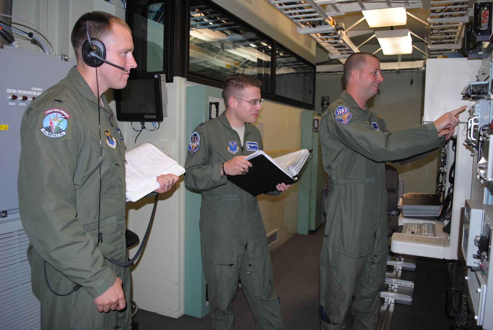 1st Lt. Daniel Hejde, 12th Missile Squadron ICBM combat crew commander, far left, watches as Capt. Ryan Hepler, 10th MS ICBM instructor combat crew commander, center, and 2nd Lt. Bryce Acres, deputy missile combat crew commander, complete a checklist during a simulated scenario in the MPT on Aug. 17. Hepler and Acres were chosen to represent the 10th Missile Squadron in the upcoming Global Strike Challenge.  Hejde is one of two trainers for the operations portion of the Global Strike Challenge. (U.S. Air Force photo/Airman 1st Class Katrina Heikkinen)