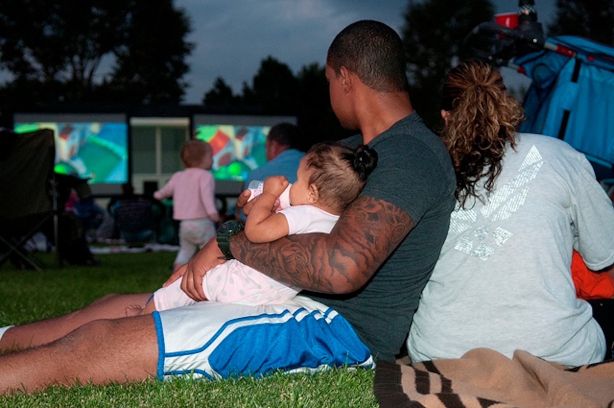 Airman 1st Class Jason Cabrera, his daughter, Madelyn, and wife, Yvonne, watch “The Lorax” with other F. E. Warren families on the parade field Aug. 17. (U.S. Air Force photo by R.J. Oriez)
