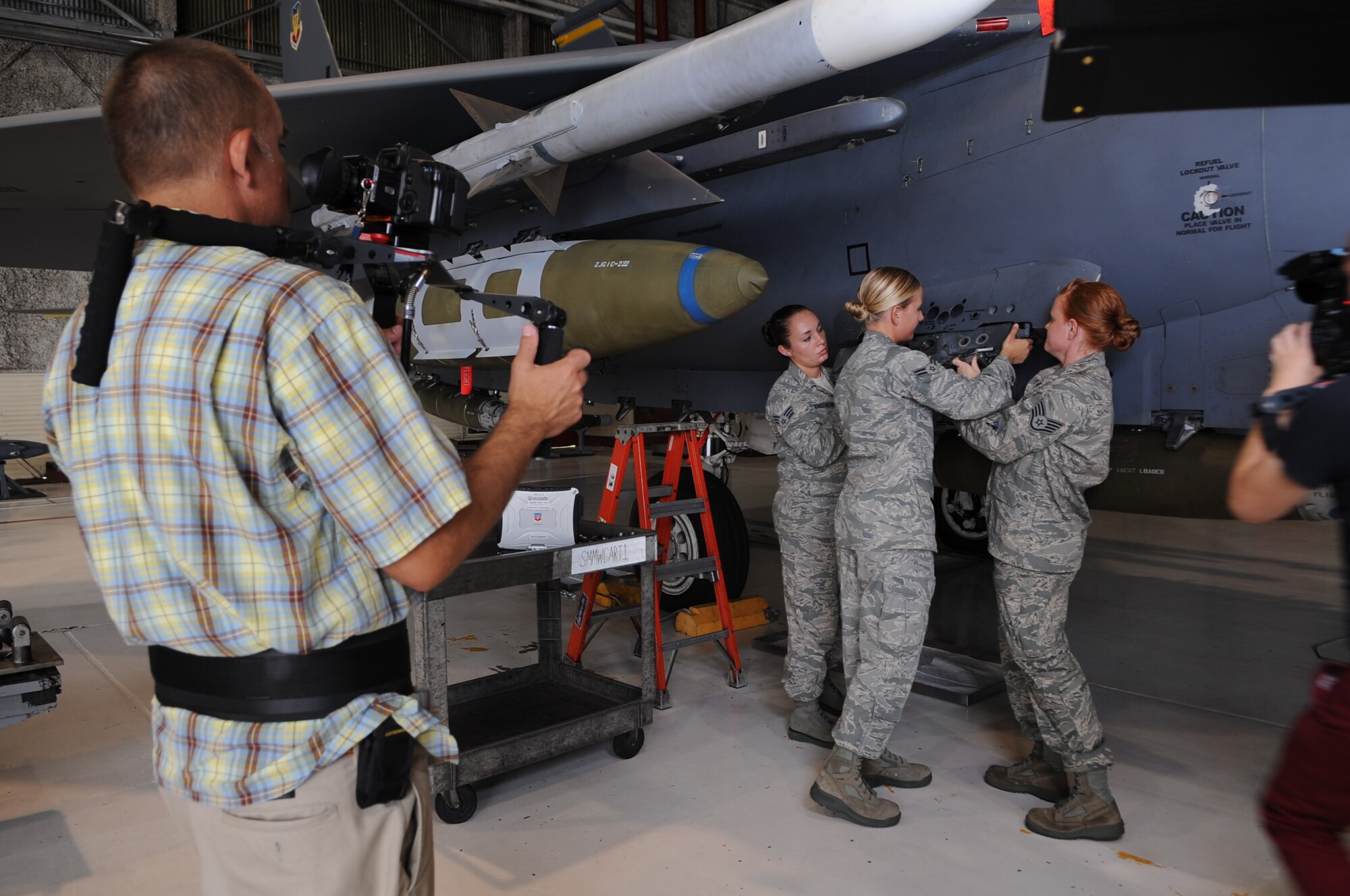 Members of the film crew record U.S. Air Force Airmen assigned to the 4th Fighter and 57th Wings as they prepare to load munitions while filming an Air Force Recruiting Service commercial on Seymour Johnson Air Force Base, N.C., Aug. 7, 2012. The weapons load crew was one of several highlighted career fields the Air Force has to offer. (U.S. Air Force photo/Airman 1st Class Aubrey Robinson/Released)