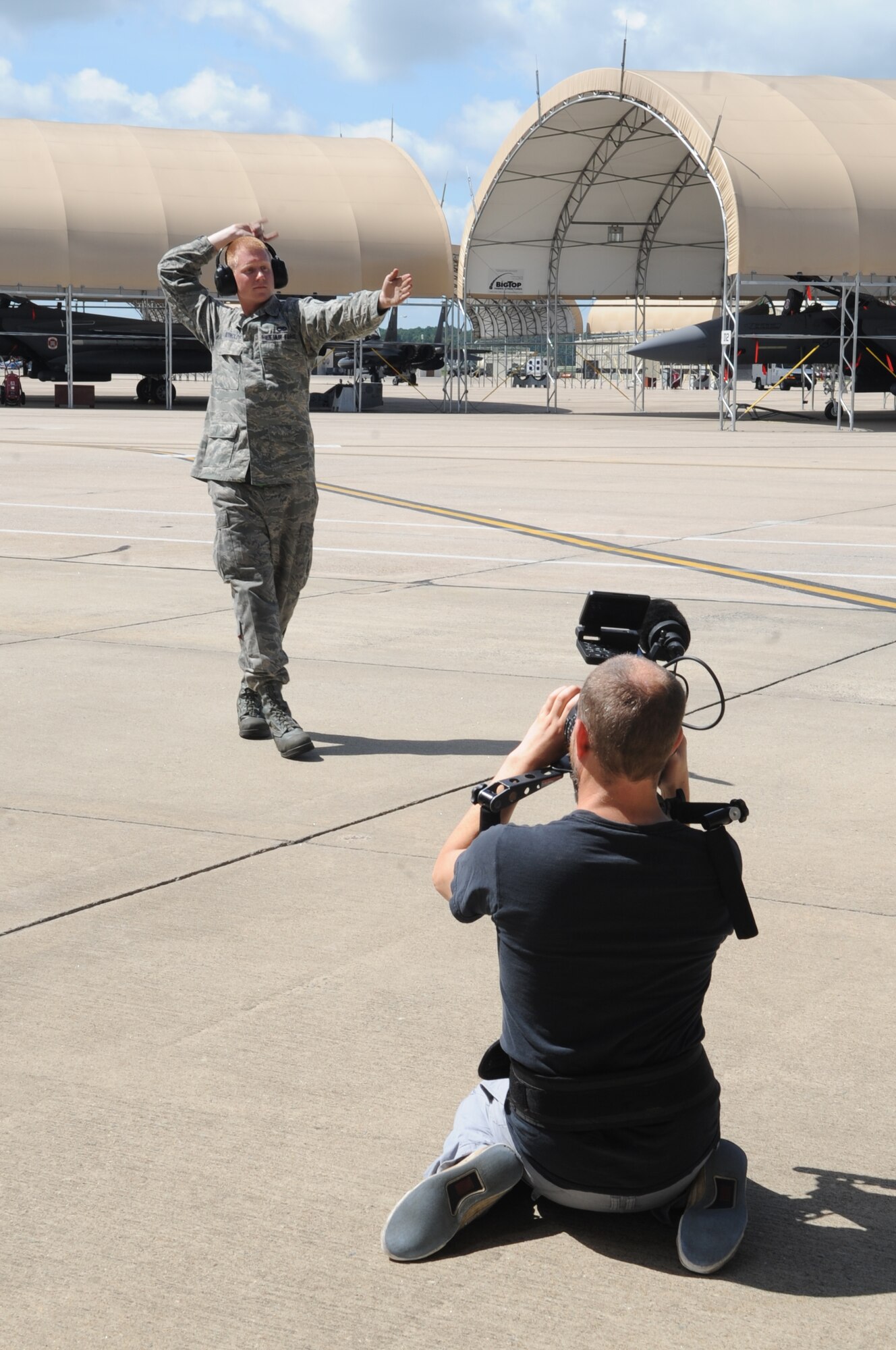 Trevor Fife, commercial director, films U.S. Air Force Airman 1st Class Dane Reynolds, 335th Aircraft Maintenance Unit crew chief, as he signals for an aircraft to advance onto the flight line during the filming of an Air Force Recruiting Service commercial on Seymour Johnson Air Force Base, N.C., Aug. 6, 2012. The commercial producers and director chose to highlight several members of Team Seymour from various career fields in order to show the diversity of jobs in the Air Force. (U.S. Air Force photo/Airman 1st Class Aubrey Robinson/Released)