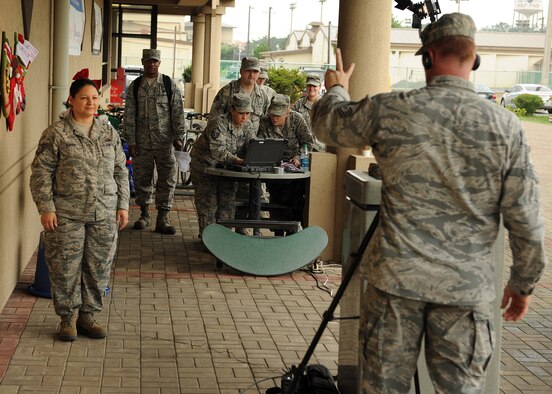 Master Sgt. John Cronin, with the Joint Hometown News Service at Fort George G. Meade, Md., conducts a hometown news video shoot while others sign up on Kunsan Air Base, Republic of Korea, Aug. 23. Hometown news videos are a chance for military members to send holiday greetings to friends and family while they are stationed around the world. (U.S. Air Force photo/Staff Sgt. Jonathan Fowler)