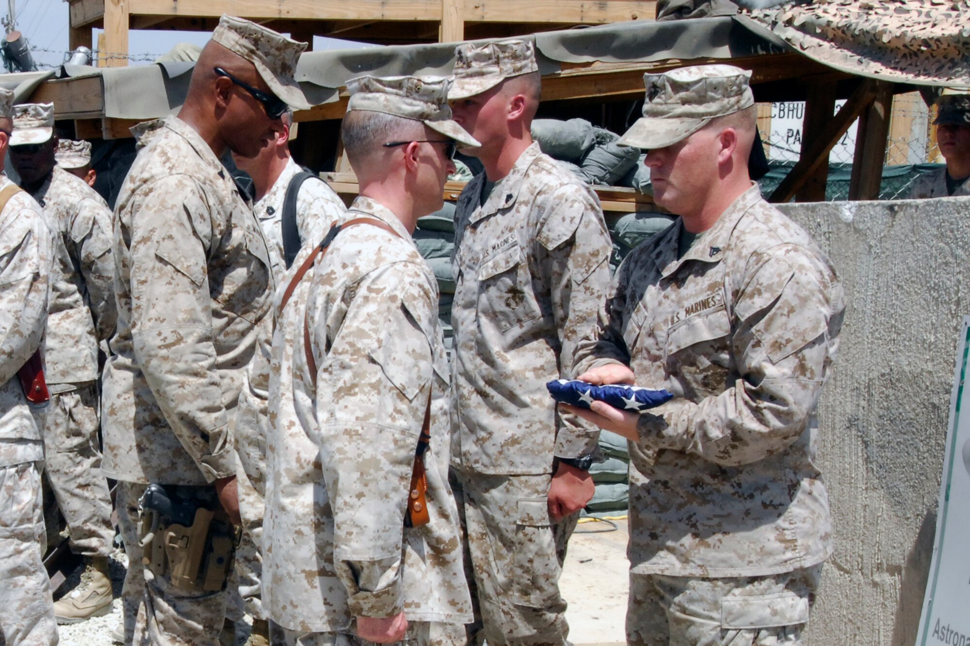 A U.S. Marine assigned to the Marine Tactical Electronic Warfare Squadron-2 presents the "Stars & Stripes" to his commander, Lt Col. Adam Musoff, VMAQ-2 commander (front left), during the Camp McCool closing ceremony at Bagram Airfield, Afghanistan, Aug. 8, 2012. The camp was named after U.S. Navy Commander William C. McCool, a space shuttle astronaut who perished when the shuttle “Columbia” broke up during reentry into Earth’s atmosphere 16 minutes before its scheduled landing. Camp McCool was opened shortly after CMDR McCool’s death. The camp had been home to the Marine Corps Prowler community since 2009. (U.S. Air Force photo/SSgt Jeff Nevison)