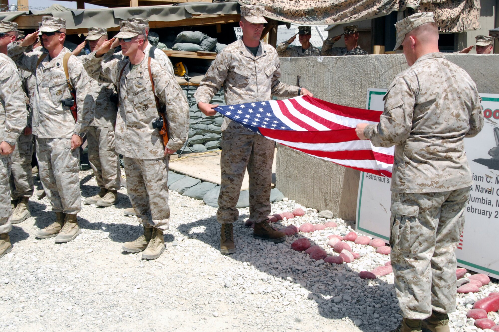 Two U.S. Marines assigned to the Marine Tactical Electronic Warfare Squadron-2, ceremonially fold a flag during the Camp McCool closing ceremony at Bagram Airfield, Afghanistan, Aug. 8, 2012. The camp was named after U.S. Navy Commander William C. McCool, a space shuttle astronaut who perished when the shuttle “Columbia” broke up during reentry into Earth’s atmosphere 16 minutes before its scheduled landing. Camp McCool was opened shortly after CMDR McCool’s death. The camp had been home to the Marine Corps Prowler community since 2009. (U.S. Air Force photo/SSgt Jeff Nevison)