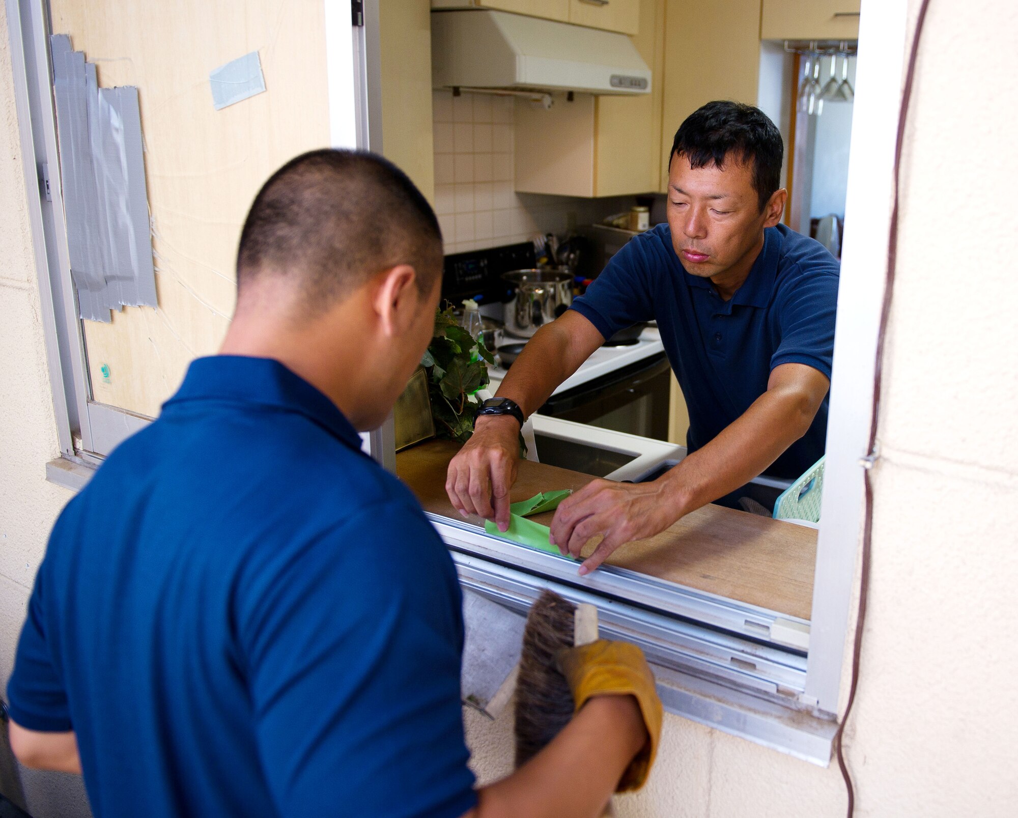 YOKOTA AIR BASE, Japan -- Tsutomu Ito, right, and Junichi Sato, 374th Civil Engineer Squadron Housing Maintenance Flight repairmen, clean broken glass out of a window frame at Yokota Air Base, Japan, on Aug. 23, 2012. Ito and Sato are one of 10 maintenance crews in charge of repairing family housing units on-base. (U.S. Air Force photo by Staff Sgt. Chad C. Strohmeyer)
