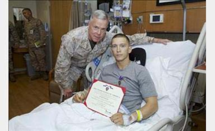 Lance Cpl. Colton Carlson being presented his Purple Heart Medal by General James Amos, Commandant of the Marine Corps.