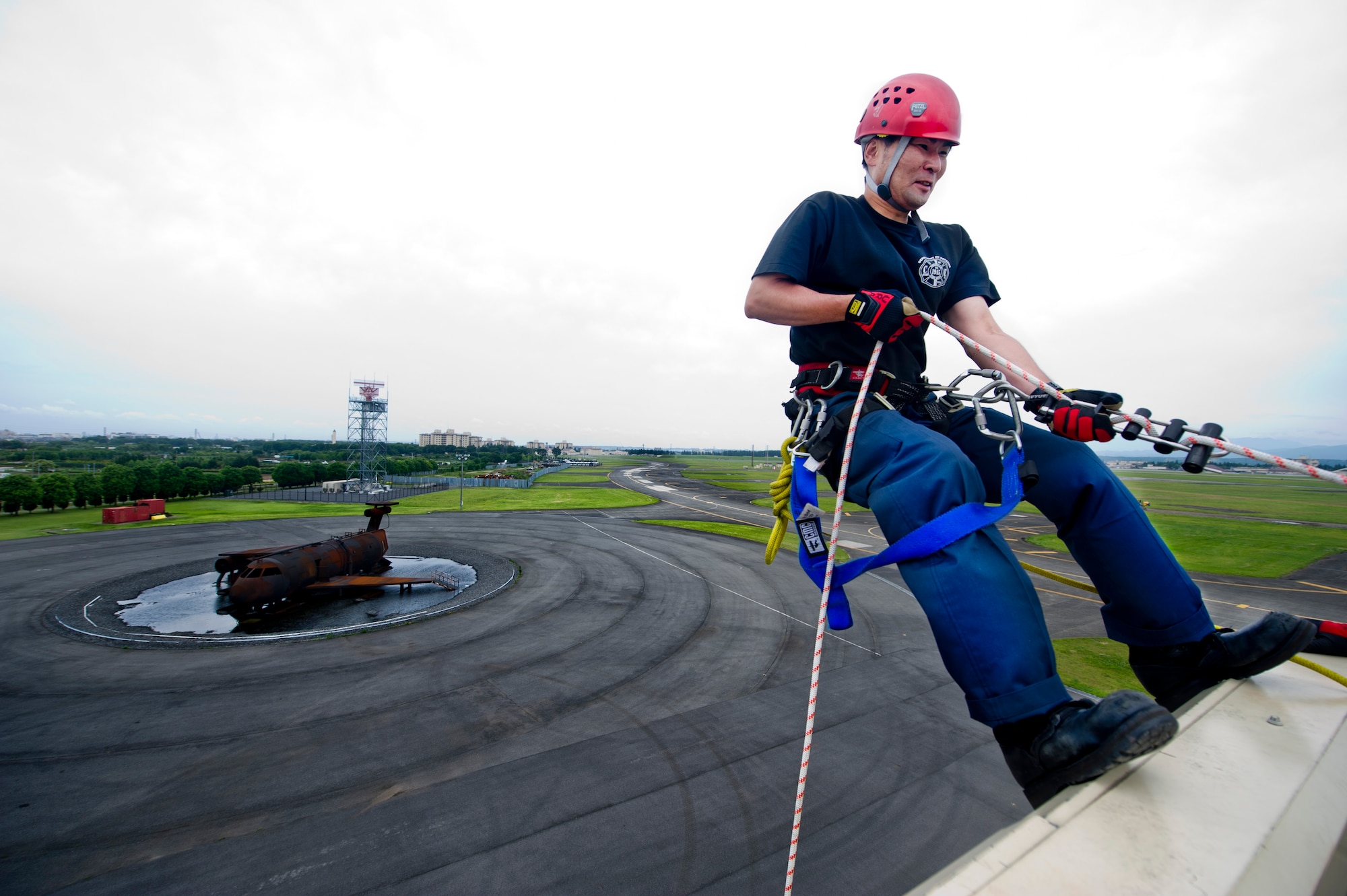 YOKOTA AIR BASE, Japan -- Mr. Kazunori Kin, 374th Civil Engineering squadron firefighter performs high-angle training at Yokota Air Base, Japan June 18, 2012. High-angle training consists of rappelling, saving stranded victims and returning them to safety. The training gives firefighters practice and confidence in their skills to negotiate tall buildings in an emergency situation. (U.S. Air Force photo by Staff Sgt. Stacy Moless)