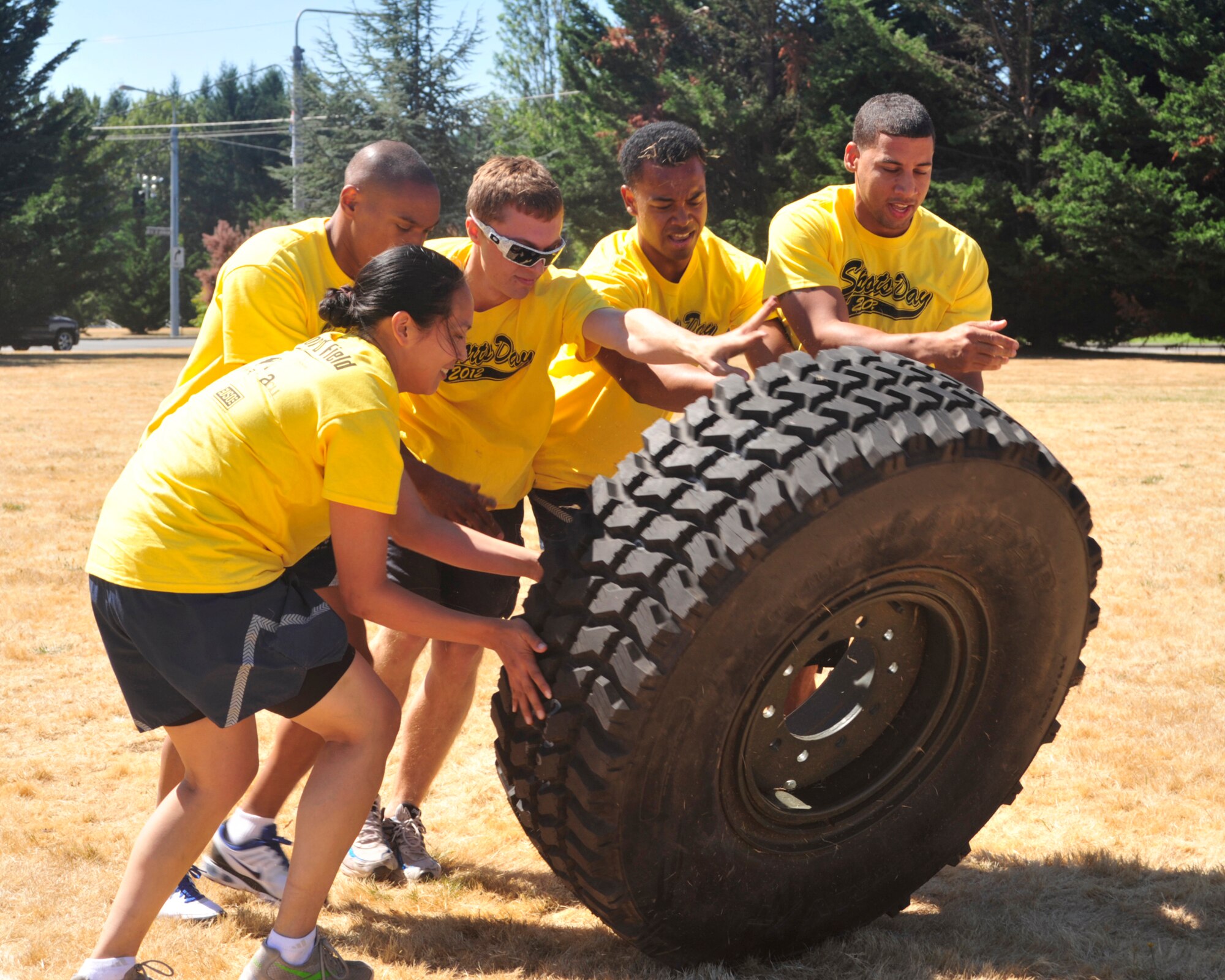 Members of the 62nd Aircraft Maintenance Squadron flip a tire as part of the combat relay race during Sports Day Aug. 24, 2012, at Joint Base Lewis-McChord, Wash. The race was one of 10 events during the day. (U.S. Air Force photo/Staff Sgt. Frances Kriss)