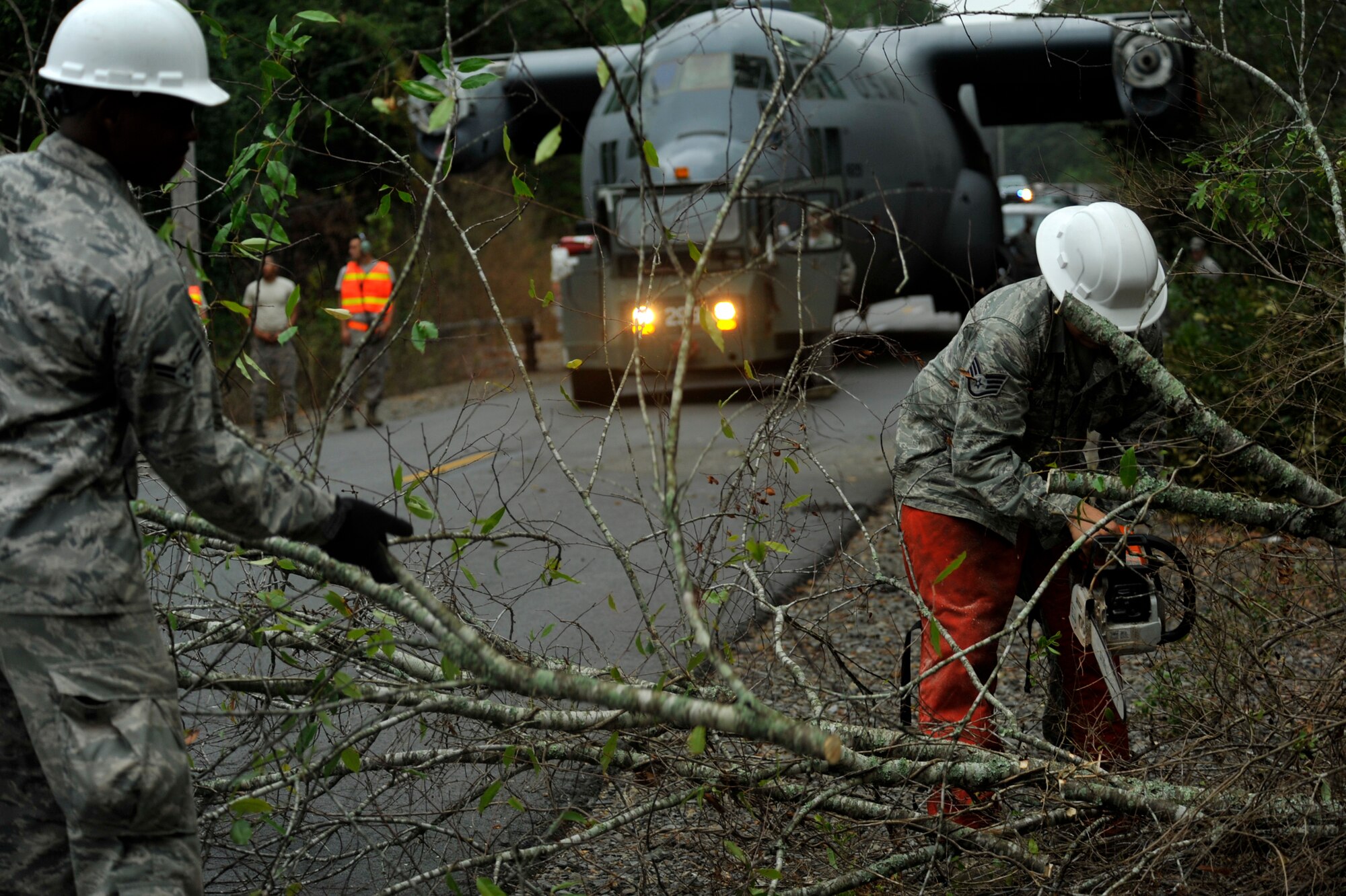 Members of the 19th Civil Engineer Squadron clear trees to make room for a C-130E being towed  to Marshall Road gate by members of the 19th Equipment Maintenance Squadron maintenance flight,  Aug. 25, 2012, at Little Rock Air Force Base, Ark. The move was a two day process from hangar 276 to the Little Rock Air Force Base - City of Jacksonville Joint Education Center. (U.S. Air Force photo by Airman 1st Class Rusty Frank)