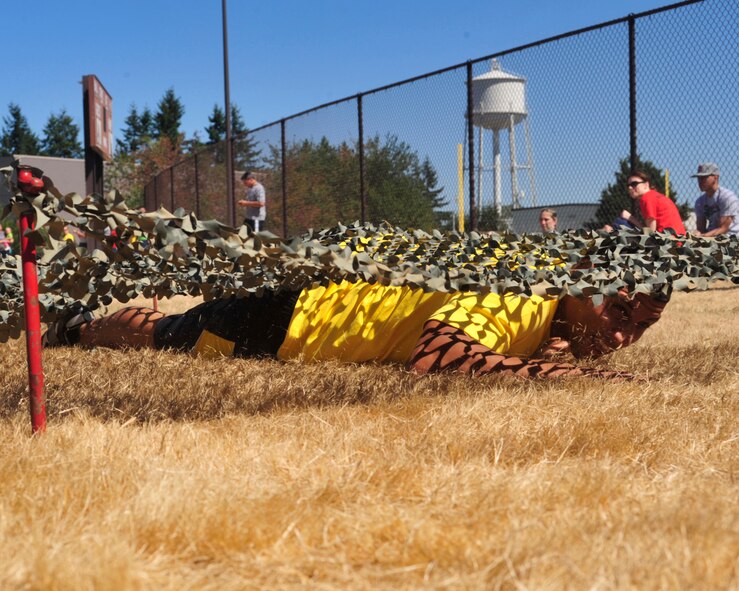 An Airman from the 62nd Aircraft Maintenance Squadron crawls under camouflage netting as part of the combat relay race during Sports Day Aug. 24, 2012, at Joint Base Lewis-McChord, Wash. Other events of the day included kickball, 3-on-3 basketball and volleyball. (U.S. Air Force photo/Staff Sgt. Frances Kriss)