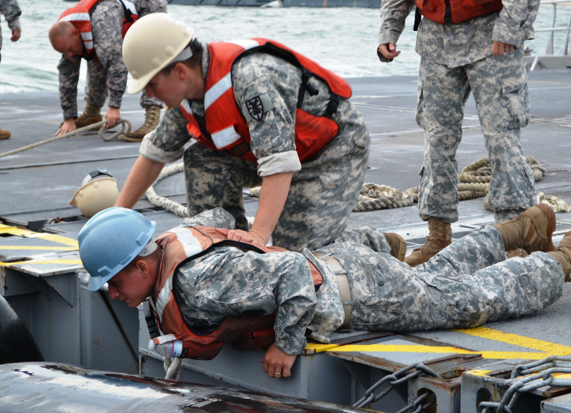 U.S. Army Pfc. Robert Byrom, right, a watercraft operator assigned to the 331st Transportation Company, 10th Transportation Battalion, 7th Sustainment Brigade, holds on to Cpl. Seth Lawson, also a watercraft operator assigned to the 331st Trans. Co., while he fixes a broken chain on an Army vessel during the Joint Logistics Over the Shore exercise at Fort Story, Va., Aug. 23. JLOTS is an annual exercise conducted around the world, and trains in the process of loading and unloading of ships. (U.S. Army photo by Staff Sgt. Alexander Burnett/ Released)