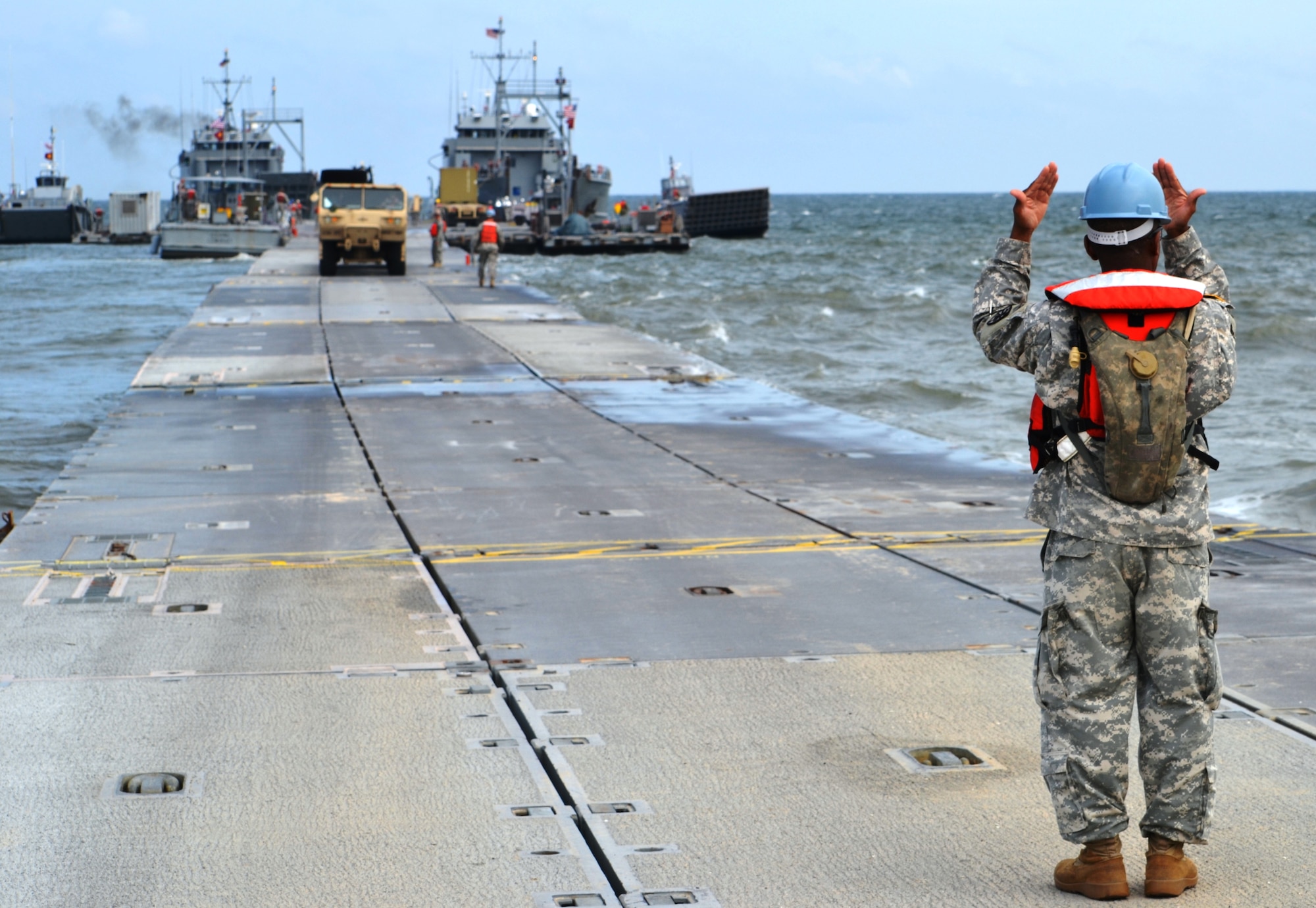 A 7th Sustainment Brigade Soldier guides a palletized load system on the causeway during the Joint Logistics Over the Shore exercise at Fort Story, Va., Aug. 23. The JLOTS exercise is a chance for Army and Navy watercraft personnel to train together on moving vehicles and equipment when no solid pier exists. (U.S. Army photo by Staff Sgt. Alexander Burnett/ Released)