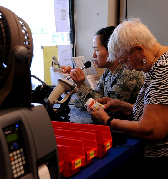 Capt. Shaoping Mo, 2nd Medical Support Squadron main pharmacy officer in charge, verifies information from a customer as Ms. Ione Barnes, volunteer, ensures the information is correct on the prescription bottle at the satellite pharmacy on Barksdale Air Force Base, La., Aug. 23. The satellite pharmacy dispenses more than 4,000 prescriptions weekly. (U.S. Air Force photo/Senior Airman La?Shanette V. Garrett)(RELEASED)