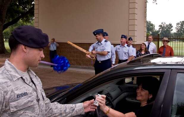 Col. Andrew Gebara, 2nd Bomb Wing commander, cuts the ribbon during the re-opening of the West Gate as Airman 1st Class Mauricio Esteves, 2nd Security Forces Squadron, checks the identification card of Barbara Makamson, 2nd Contracting Squadron, on Barksdale Air Force Base, La., Aug. 27. The $415,000 project now provides 2 SFS members cover from weather and enhances base security. (U.S. Air Force photo/Senior Airman La?Shanette V. Garrett)(RELEASED) 