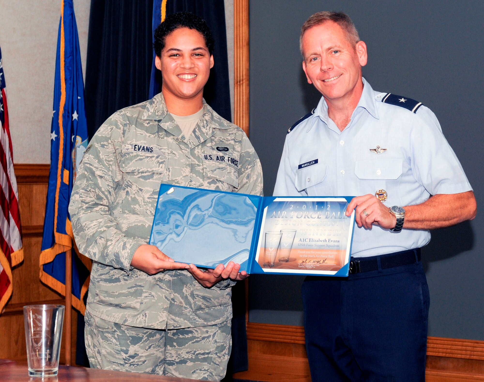 Brigadier Gen. John McMullen, 325th Fighter Wing commander, presents Airman 1st Class Elizabeth Evans, 325th Force Support Squadron customer service apprentice, with a certificate of appreciation for her winning design for the 65th Annual U.S. Air Force Ball. The design will be showcased on memorabilia at the Ball. (U.S. Air Force photo by Christopher Cokeing) 