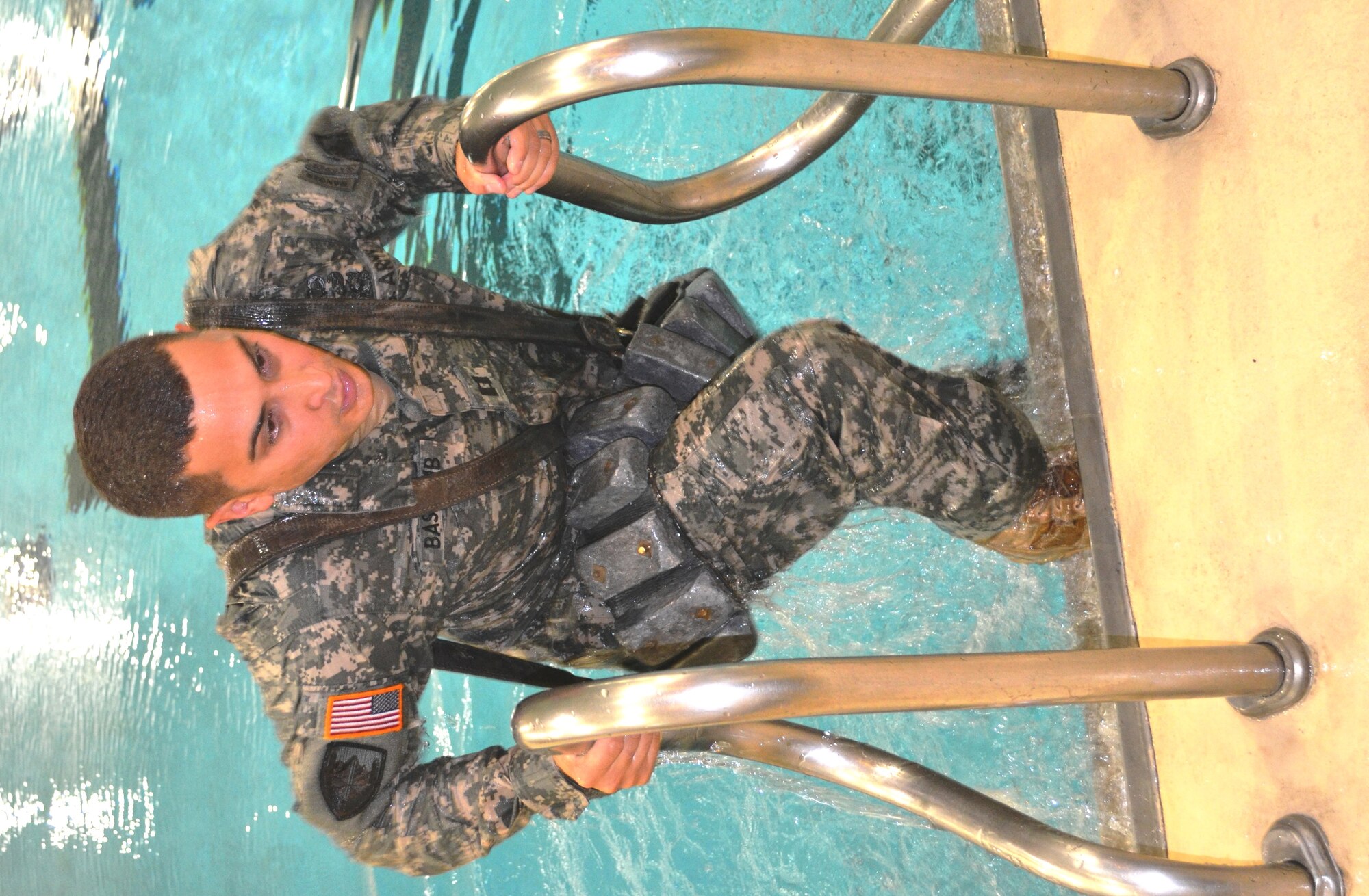 Capt. Gregory Bascomb, the incoming 511th Dive Detachment commander, climbs out of the pool after walking and swimming his way across with an 84-lb. weight harness around him during a change of command ceremony at the Aquatic Center on Fort Eustis, Aug. 24. The harness was used with the Mach-5 dive suit to keep divers from rising due to the amount of air in their suits and helmets. (Photo by Staff Sgt. Alexander Burnett)