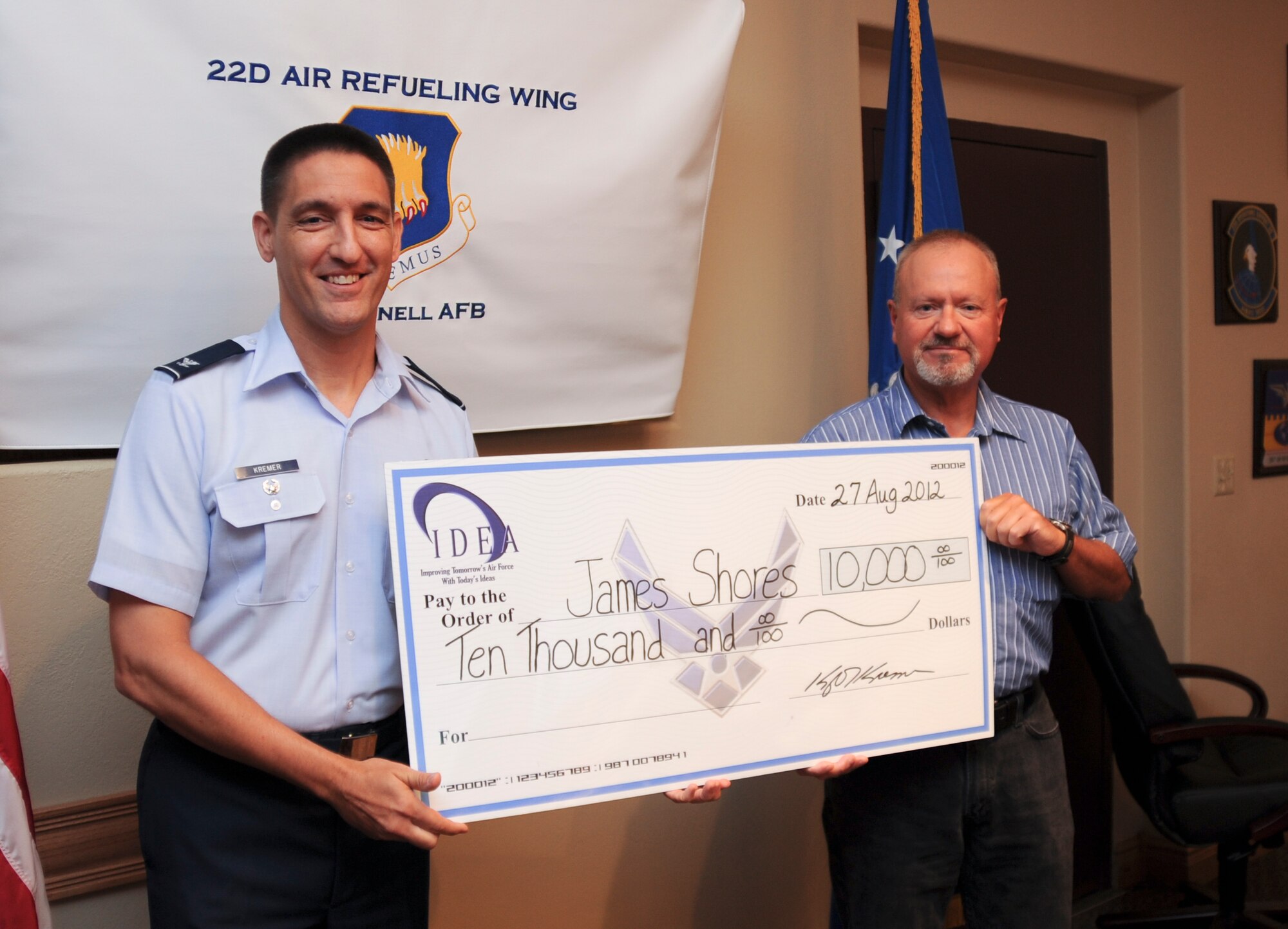 Jim Shores, 22nd Operations Support Squadron short range scheduling chief, is presented a $10,000 check by Col. Kyle Kramer, 22nd Air Refueling Wing vice commander, during a wing staff meeting Aug. 27, 2012, McConnell Air Force Base, Kan. Shores was awarded the money through the Innovative Development Through Employee Awareness Program, which provides an incentive for members to submit ideas that streamline processes and increase productivity and efficiency in the workplace. (U.S. Air Force photo/Airman 1st Class Jose L. Leon)