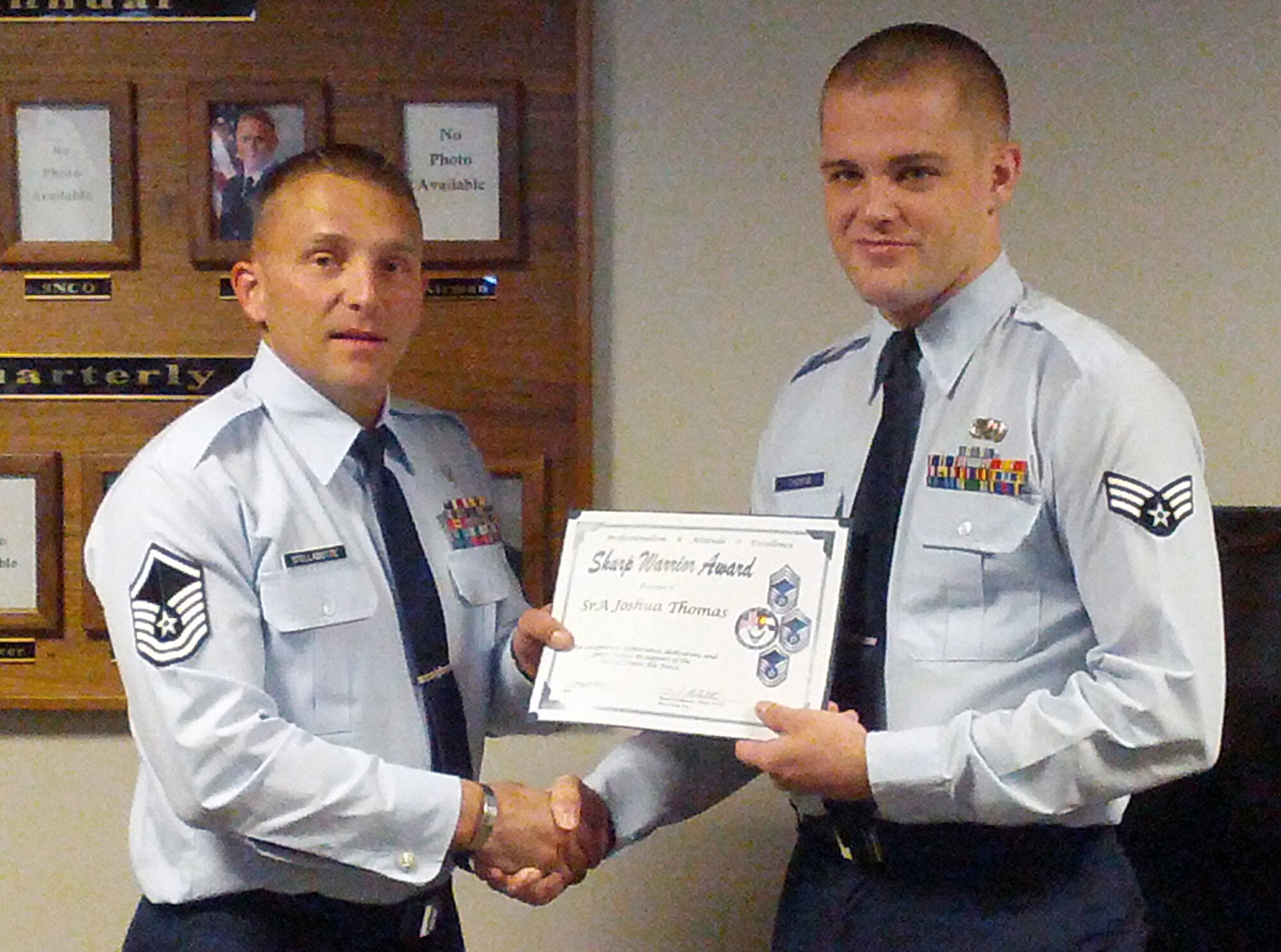 PETERSON AIR FORCE BASE, Colo. -- Master Sgt. Dan Stellabotte, 21st Force Support Squadron, presents the July Sharp Warrior Award on behalf of the Pikes Peak Top 3 to Senior Airman Joshua Thomas, 21st Comptroller Squadron. According to the Pikes Peak Top 3, the award is based on the whole person concept. Thomas exemplified that through his involvement with the Junior Enlisted Association and Booster Club, along with volunteering with the Waldo Canyon fire relief. (U.S. Air Force photo/Staff Sgt. James Blaz)