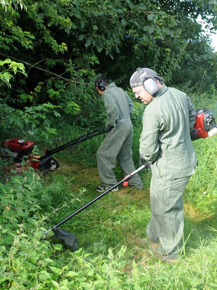 BECK ROW, England – Master Sgt. Eric Leirer, 352nd Special Operations Maintenance Squadron, and his 13-year-old son Albert Valen, clear weeds and foliage from the backyard of a disabled resident in Beck Row, a community just outside RAF Mildenhall, Aug. 25, 2012. Leirer said he volunteered to get his son involved in the local community and instill the same ideals and values he has. (U.S. Air Force photo/Staff Sgt. Austin M. May)