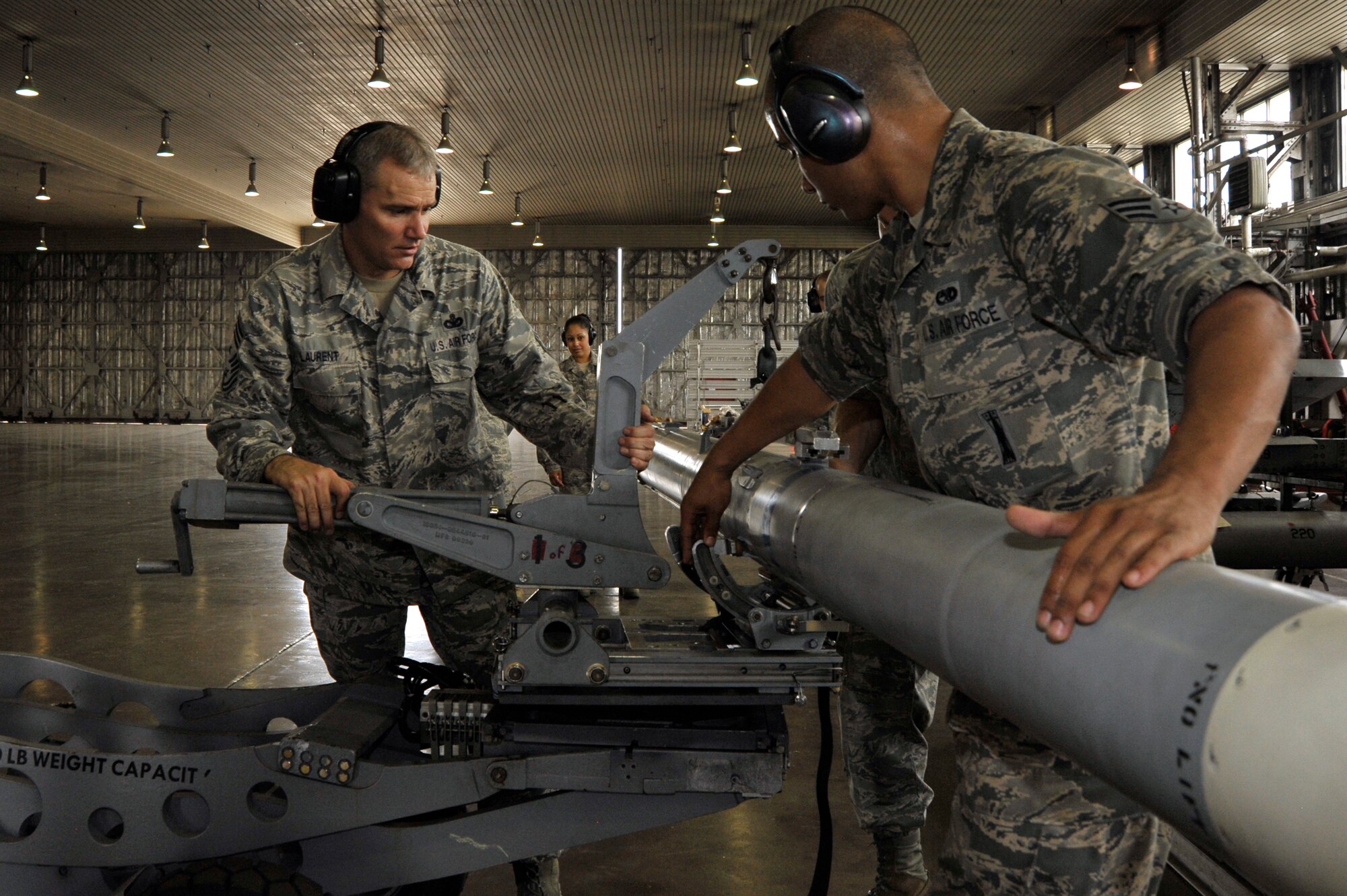 U.S. Air Force Chief Master Sgt. James Laurent, left, 35th Fighter Wing command chief, helps Senior Airman Kahlil Bashir, 35th Maintenance Group squadron lead crew member, load an AIM-120 advanced medium-range air-to-air missile onto a MJ-1 lift truck at Misawa Air Base, Japan, Aug. 24, 2012. The F-16 can carry a payload of two 2,000-pound bombs, two AIM-9, two AIM-120 and two 2400-pound external fuel tanks. (U.S. Air Force photo by Staff Sgt. Nathan Lipscomb/Released)