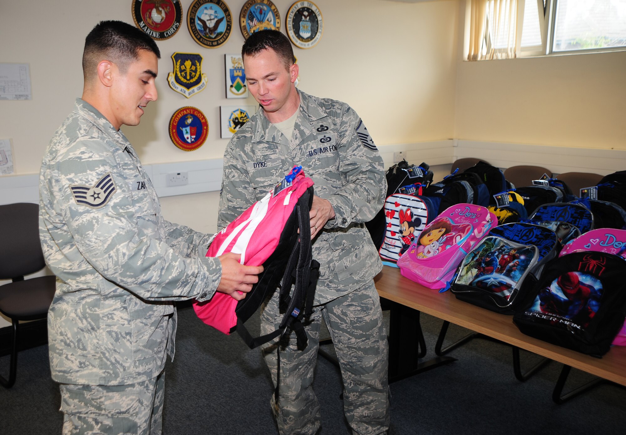 RAF MENWITH HILL, United Kingdom - Staff Sgt. Shawn Zapata, 421st Logistics Flight, receives a backpack full of school supplies from Master Sgt. Dennis Dyke, Aug. 3. Operation Warmheart, through the RAF Menwith Hill First Sergeant Council, gave free school supplies to 25 children in grades K-12, from the Menwith Hill Community during the first ever “Operation Back-to-School.” In addition to providing school supplies to families which meet eligibility requirements, Operation Warmheart also gives families meal voucher/gift cards during the holiday seasons, as well as giving meals to family members on Deployed Family Member Night at the club. For more information, contact a member of the first sergeant council. (U.S. Air Force photo by Staff Sgt. Brok McCarthy)