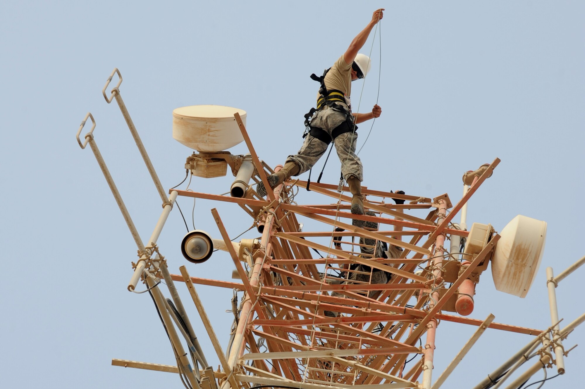 U.S. Air Force Senior Airman Cyrus Torres lowers a rope prior to moving two high frequency ground-to-air antennas in Southwest Asia, August 7, 2012. The move is in preparation for the construction material holding yard for the Technical Control Facility and Network Control Center expansion. Torres is assigned tot he 379th Expeditionary Communication Squadron and is deployed from Aviano Air Base, Italy. (U.S. Air Force photo/Staff Sgt. Sheila deVera)