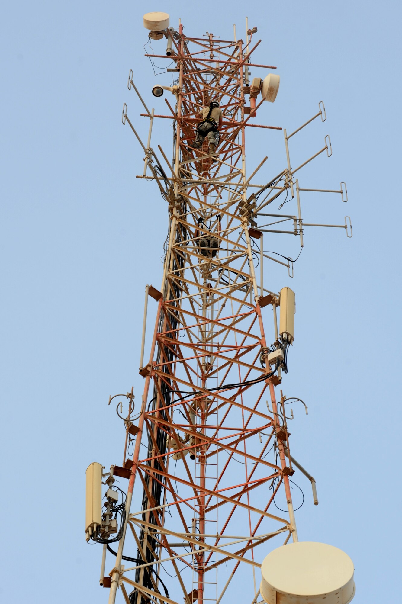 U.S. Air Force Staff Sgt. Levi Hakola (inside) and Senior Airman Cyrus Torres, both assigned to the 379th Expeditionary Communication Squadron, scale the 150 foot tall communication tower moving two high frequency ground-to-air antennas in Southwest Asia, August 7, 2012. The move is in preparation for the construction material holding yard for the Technical Control Facility and Network Control Center expansion. Hakola is deployed from Ramstein Air Base, Germany and Torres is from Aviano Air Base, Italy. (U.S. Air Force photo/Staff Sgt. Sheila deVera)