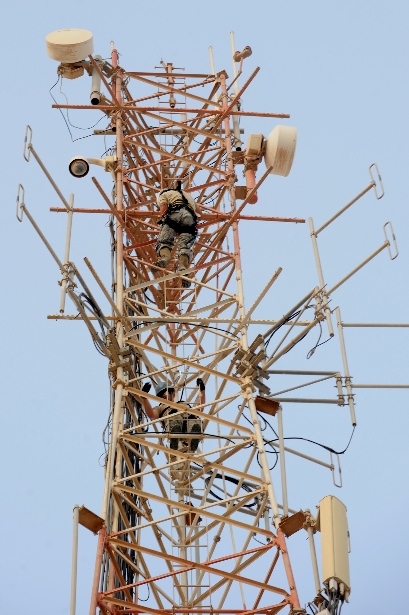 U.S. Air Force Staff Sgt. Levi Hakola (inside) and Senior Airman Cyrus Torres, both assigned to the 379th Expeditionary Communication Squadron, scale the 150 foot tall communication tower moving two high frequency ground-to-air antennas in Southwest Asia, August 7, 2012. The move is in preparation for the construction material holding yard for the Technical Control Facility and Network Control Center expansion. Hakola is deployed from Ramstein Air Base, Germany and Torres is from Aviano Air Base, Italy. (U.S. Air Force photo/Staff Sgt. Sheila deVera)