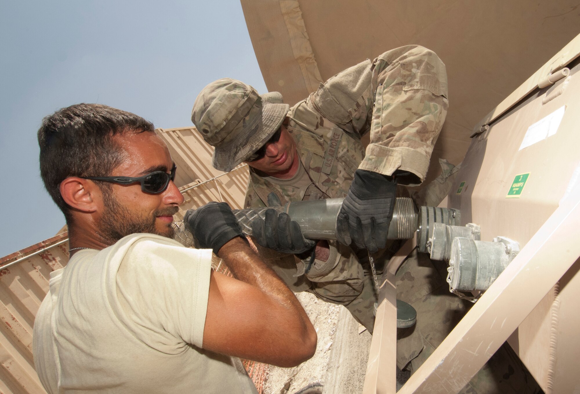 SrA Jefferson Harkleroad (front), 455th Expeditionary Civil Engineer Squadron electrician, and SSgt Ryan Capson, 455 ECES Heating, Ventilation and Air Conditioning craftsman, attach cables to a power distribution panel for one of the Alaska transient tents built at Bagram Airfield, Afghanistan, Aug. 23, 2012. A crew of 14 Airmen constructed the tents in two days, working in temperatures above 100 degrees. The tents were built to temporarily house transient Airmen. (U.S. Air Force photo/SSgt Jeff Nevison) 