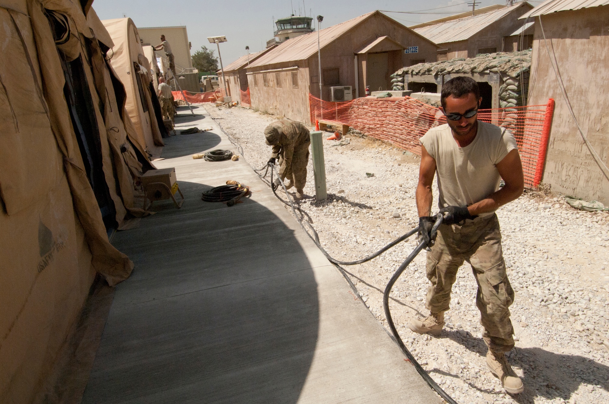 SrA Jefferson Harkleroad (front), 455th Expeditionary Civil Engineer Squadron electrician, and SSgt Ryan Capson, 455 ECES Heating, Ventilation and Air Conditioning craftsman, run cables to each of the six Alaska transient tents constructed at Bagram Airfield, Afghanistan, Aug. 23, 2012. A crew of 14 Airmen constructed the tents in two days, working in temperatures above 100 degrees. The tents were built to temporarily house transient Airmen. (U.S. Air Force photo/SSgt Jeff Nevison) 