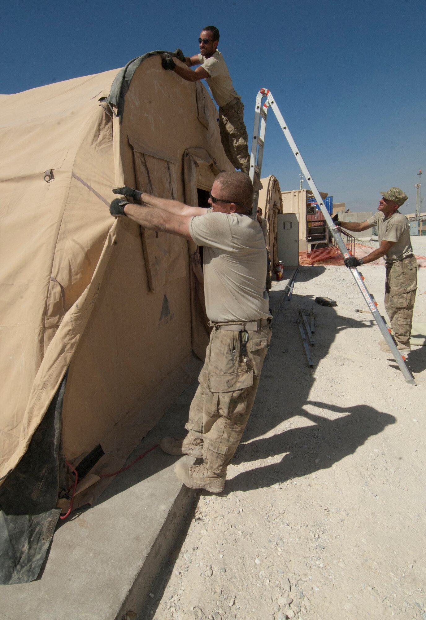 Airmen assigned to the 455th Expeditionary Civil Engineer Squadron secure and tighten the canvas cover for one of the six Alaska transient tents at Bagram Airfield, Afghanistan, Aug. 22, 2012. The crew of 14 Airmen constructed the tents in two days, working in temperatures above 100 degrees. The tents were built to temporarily house transient Airmen. (U.S. Air Force photo/SSgt Jeff Nevison) 