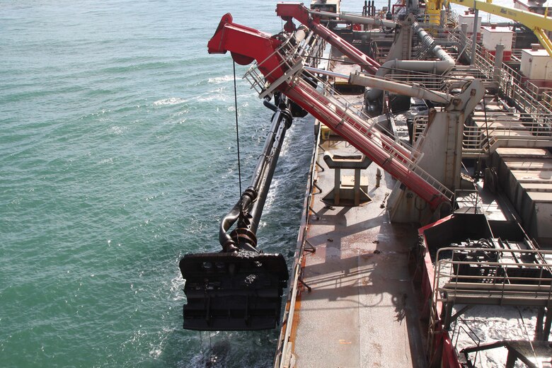 The arm of the hopper dredge is lowered to the harbor floor where it sucks material onto the vessel.