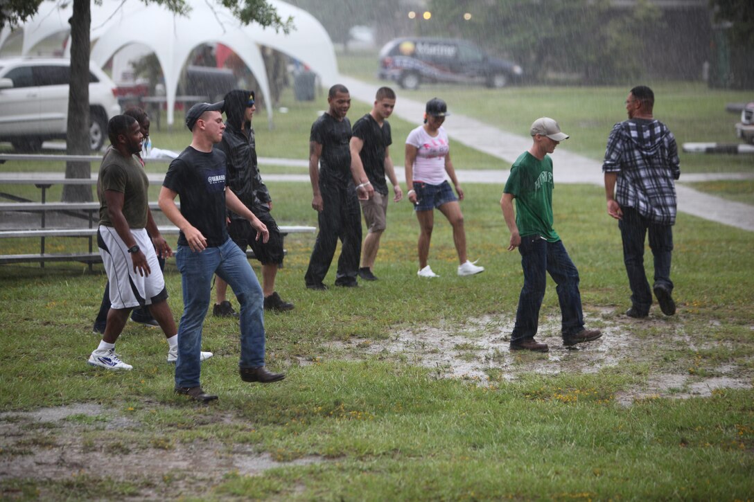 A Group of Marines and sailors with 2nd Marine Logistics Group dance in the rain during a barracks bash aboard Camp Lejeune, N.C., Aug. 22, 2012. The event started early in the afternoon with a flag football tournament.  After the tournament, servicemembers enjoyed bouncy houses, rock climbing, sumo wrestling, tug-of-war and a hypnotism show.  The participants also had the opportunity to purchase tickets for raffles to win gift cards, a TV, a DVD player and two bicycles throughout the event. 